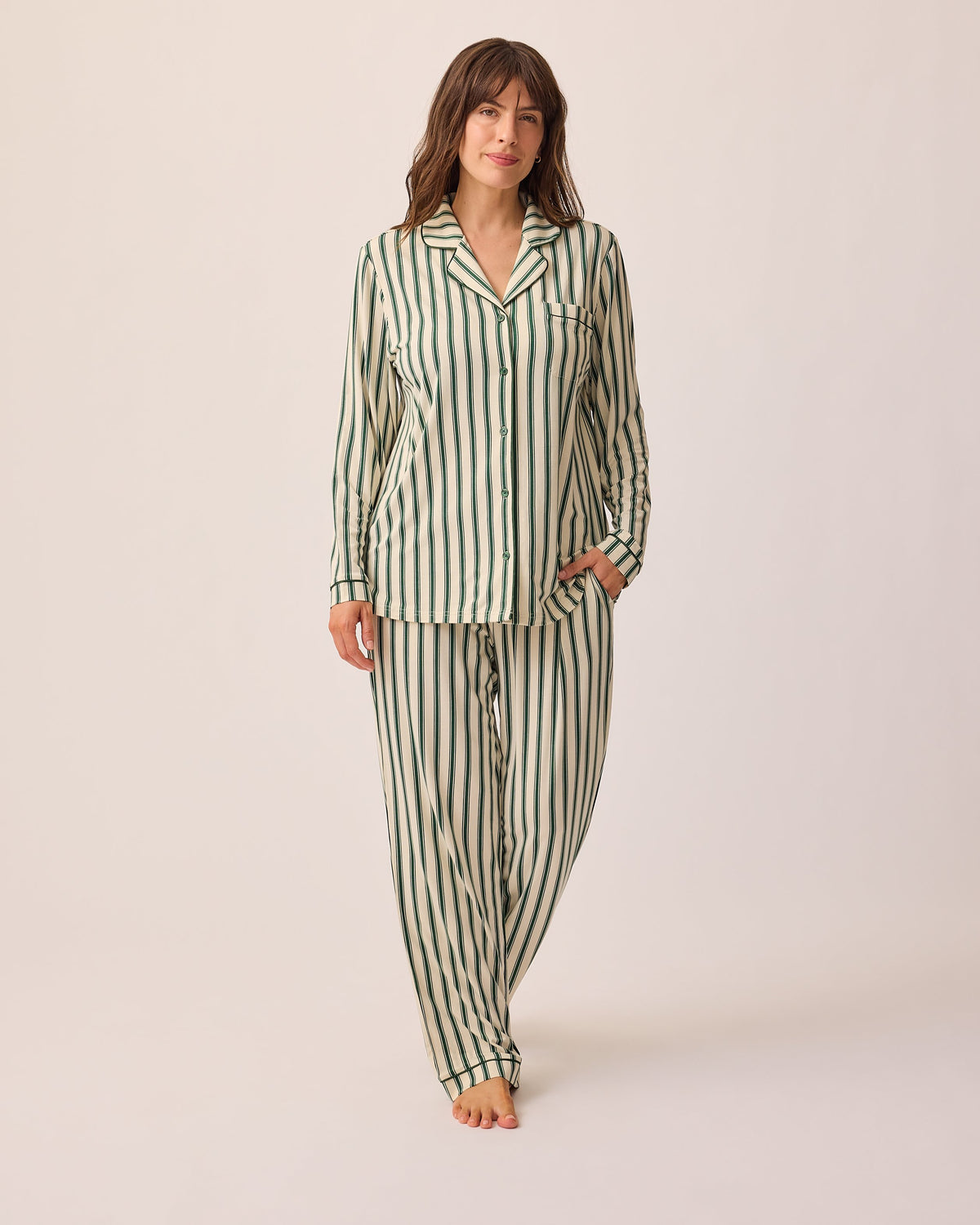 Model is wearing Clea Bamboo Long Sleeve Pajama Set in Green Candy Stripe, on a beige background.@model_info:KJ is 5'9" and wearing a Medium.