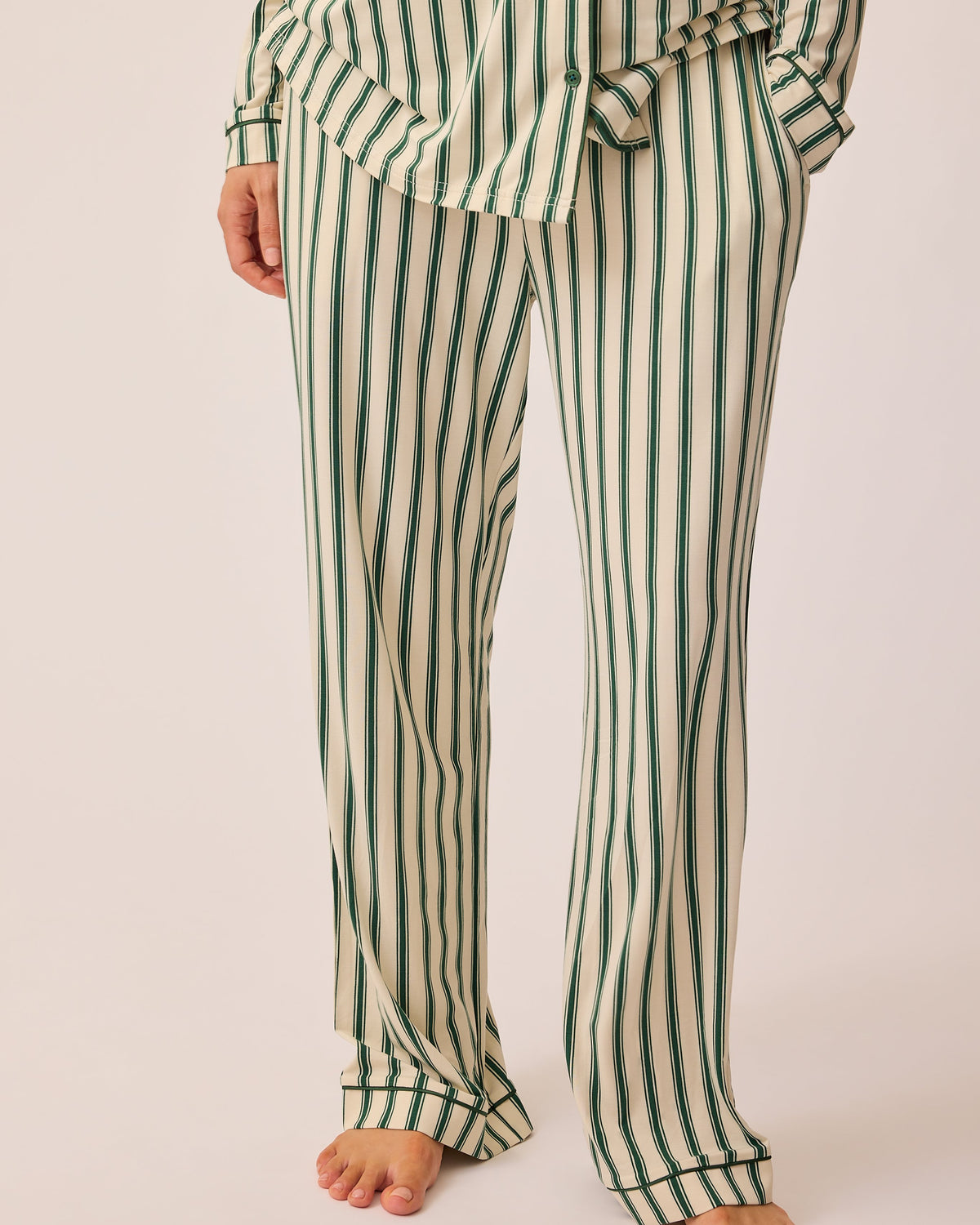 Close up of pants on Clea Bamboo Long Sleeve Pajama Set in Green Candy Stripe, on a beige background.