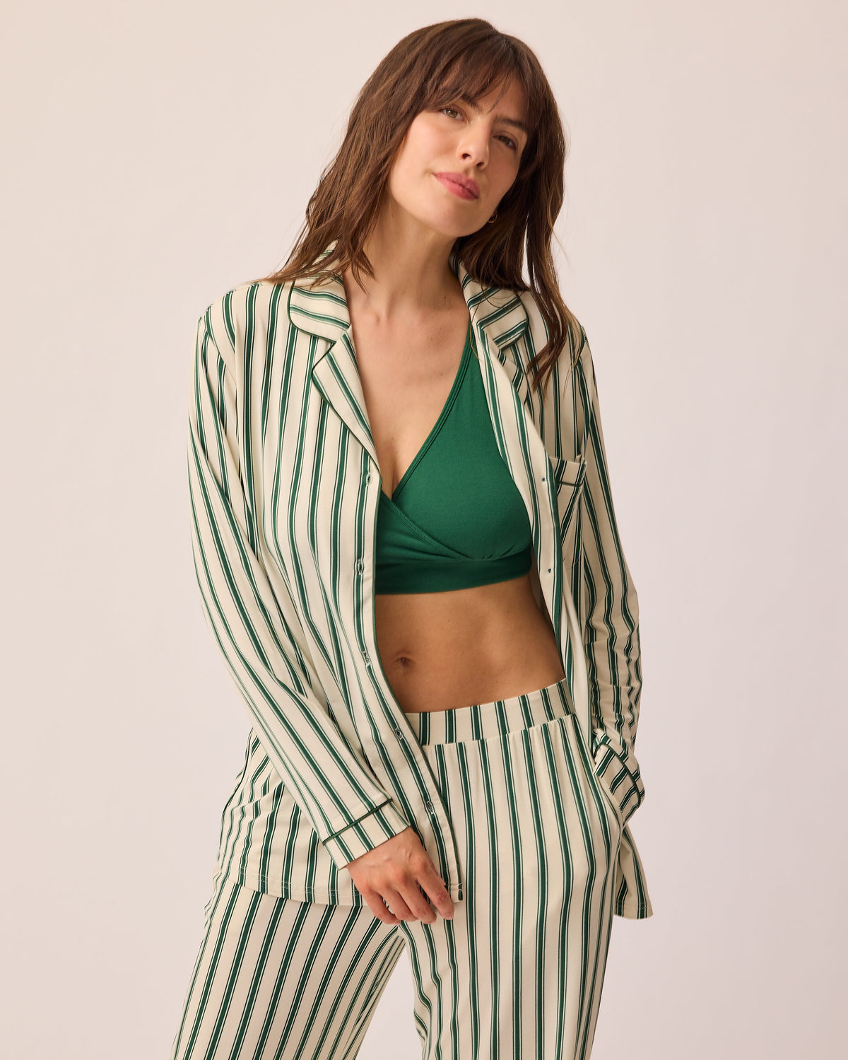 Model with top open to show nursing access on the Clea Bamboo Long Sleeve Pajama Set in Green Candy Stripe, on a beige background.