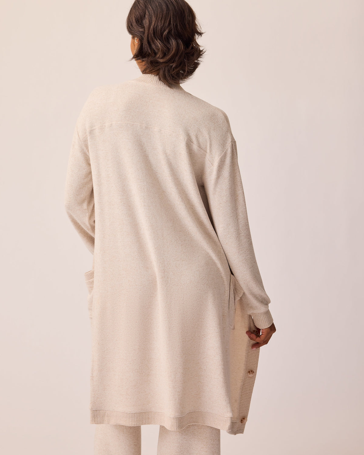 Back view of CozyKnit Wide Leg Lounge Pant in Oat, and CozyKnit Long Cardigan in Oat, on a beige background.