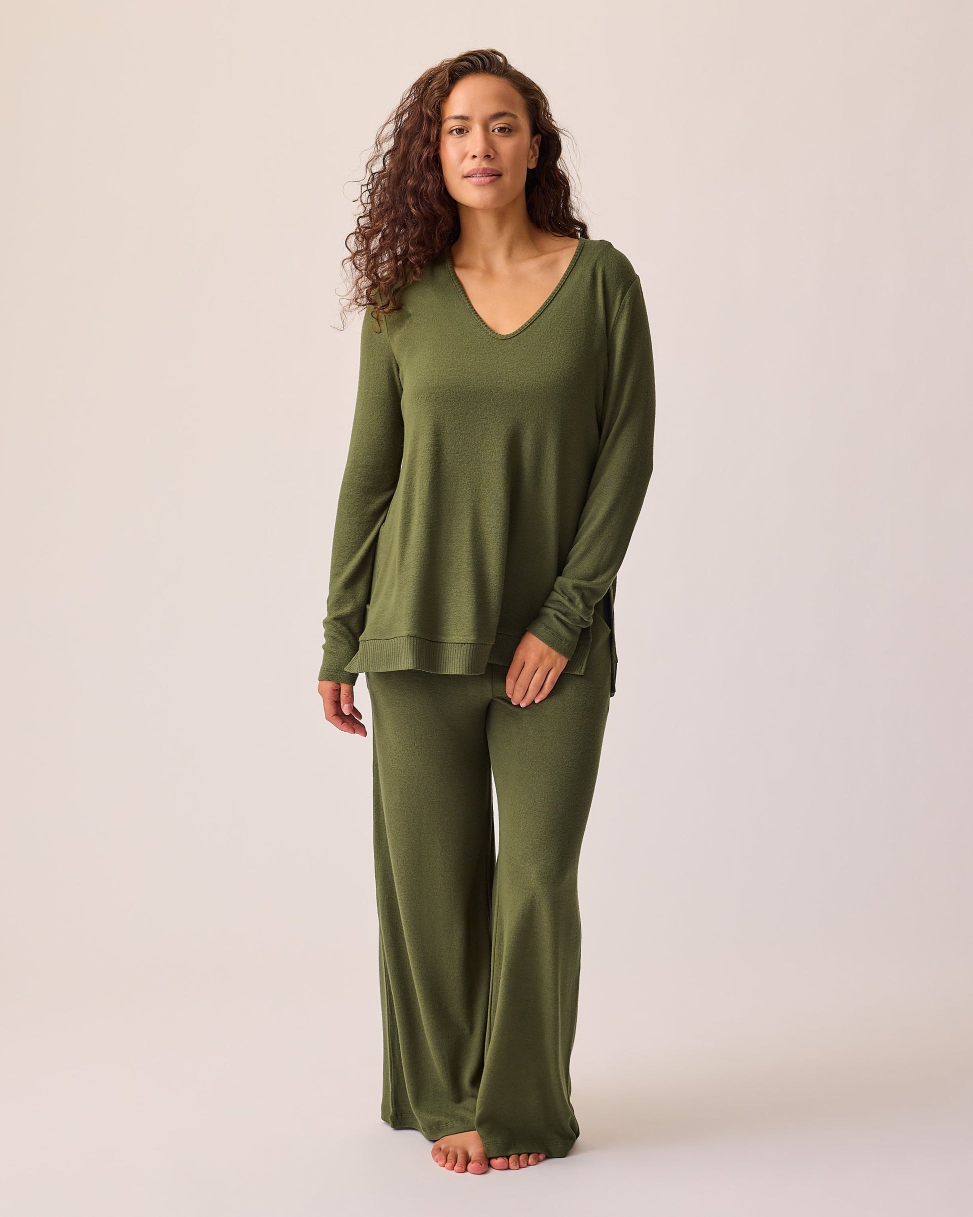 Model is wearing CozyKnit Wide Leg Lounge Pant in Deep Olive and CozyKnit Maternity & Nursing V-neck Top in Deep Olive on a beige background.
