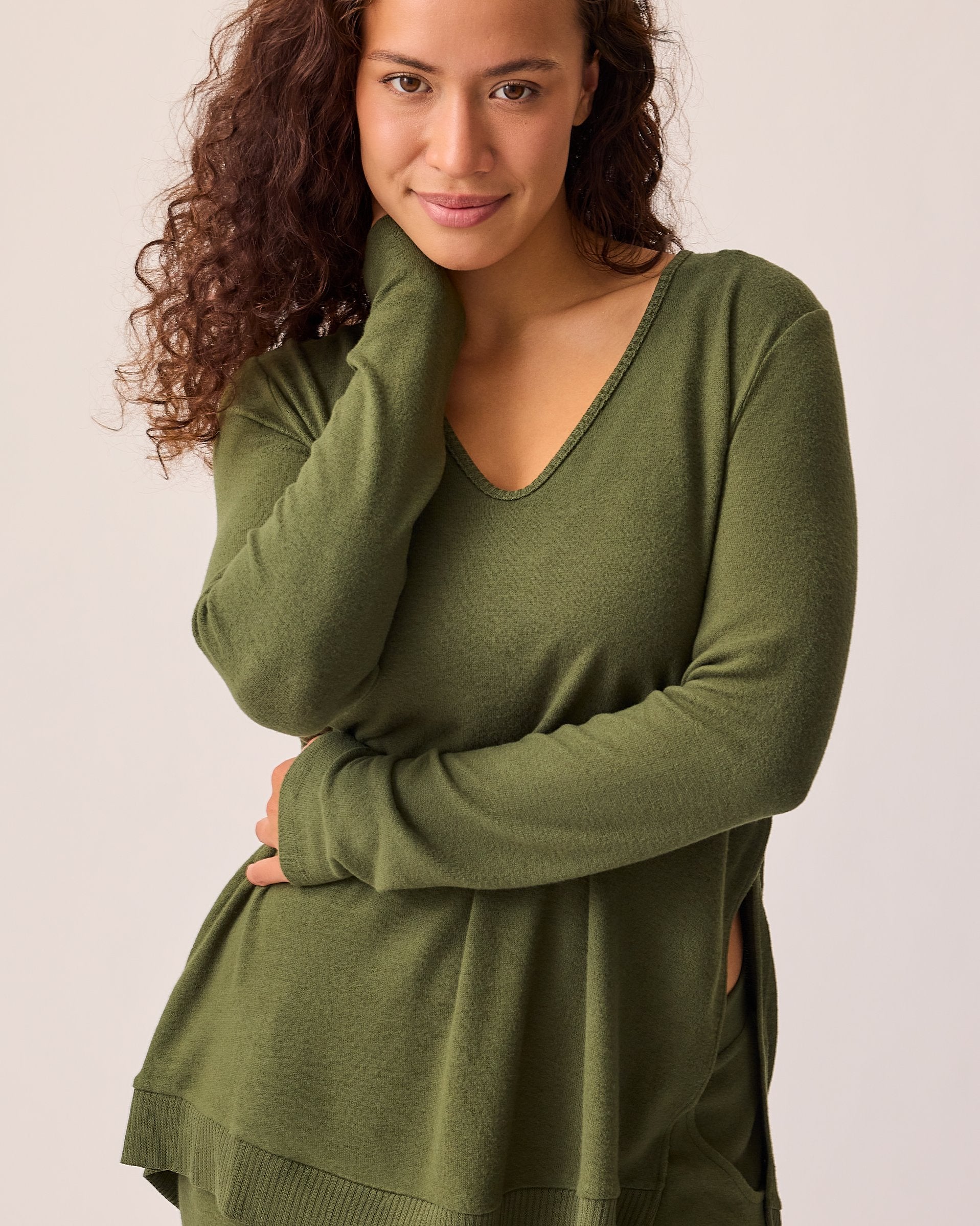Model is wearing CozyKnit Maternity & Nursing V-neck Top in Deep Olive on a beige background. 
