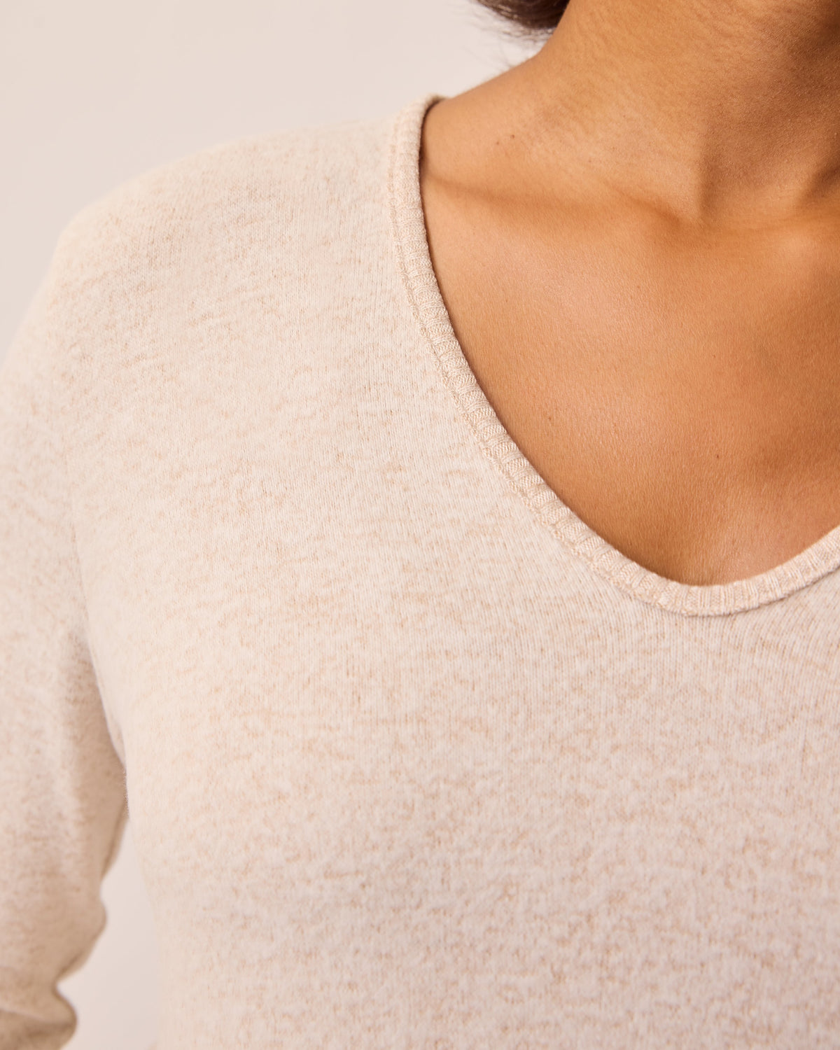 Close up of V-neck on the CozyKnit Maternity & Nursing V-neck Top in Oat on a beige background.