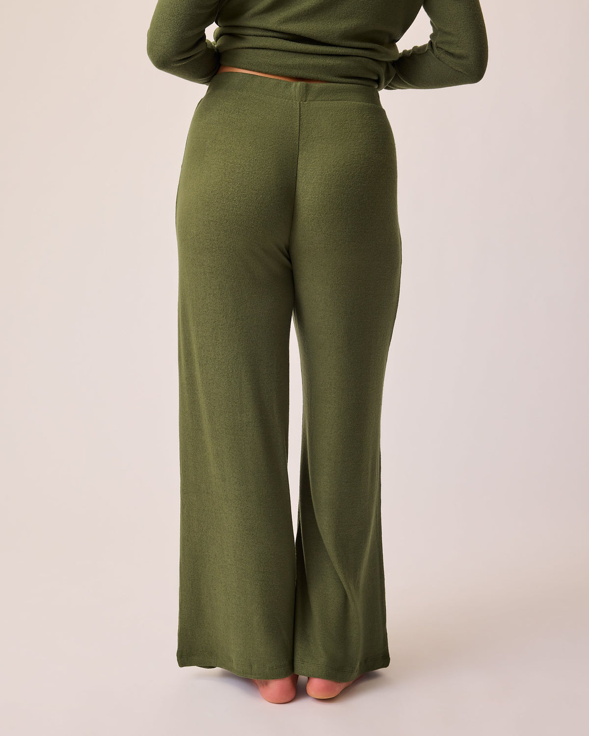 Back view of model wearing CozyKnit Wide Leg Lounge Pant in Deep Olive on a beige background.
