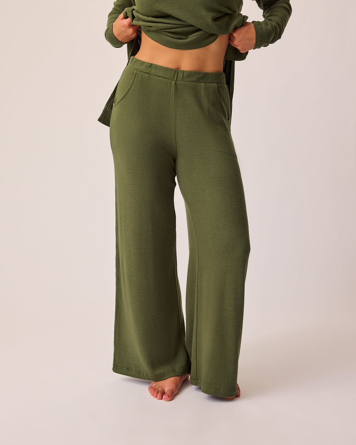 Model is wearing CozyKnit Wide Leg Lounge Pant in Deep Olive on a beige background. @model_info:Sadie is 5'8" and wearing a Medium.