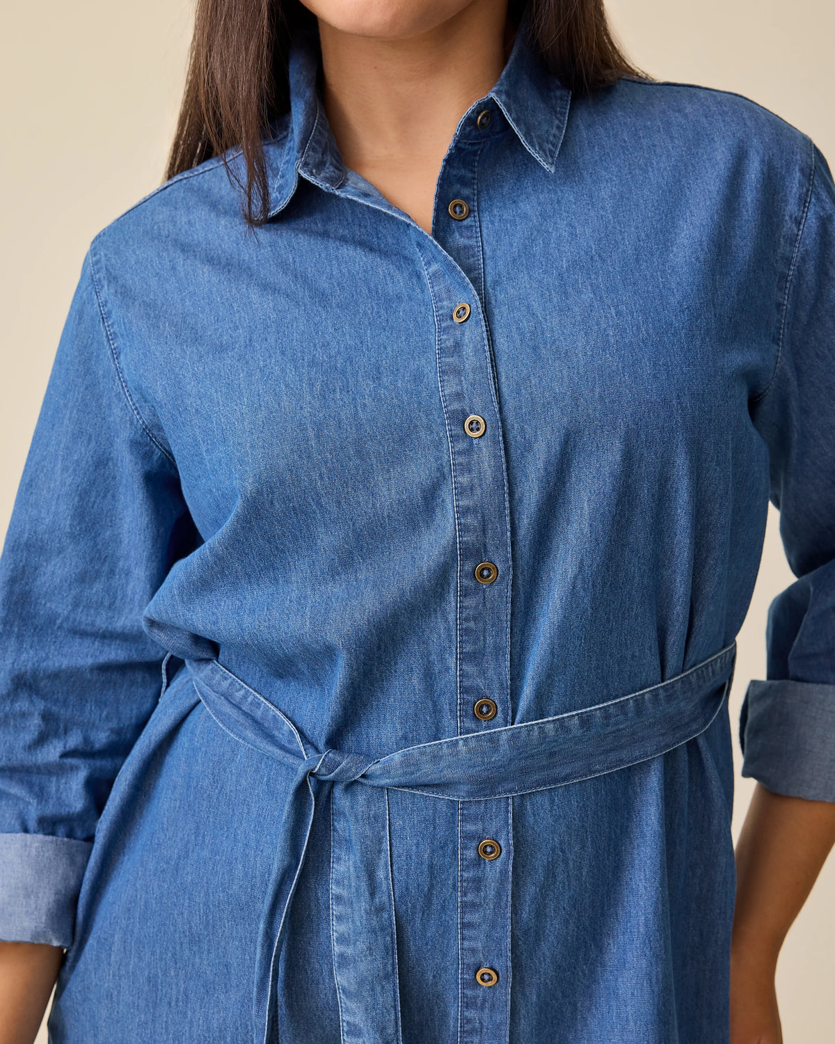 Close up of denim belt on Denim Maternity & Nursing Shirt Dress in Dark Wash on a beige background.