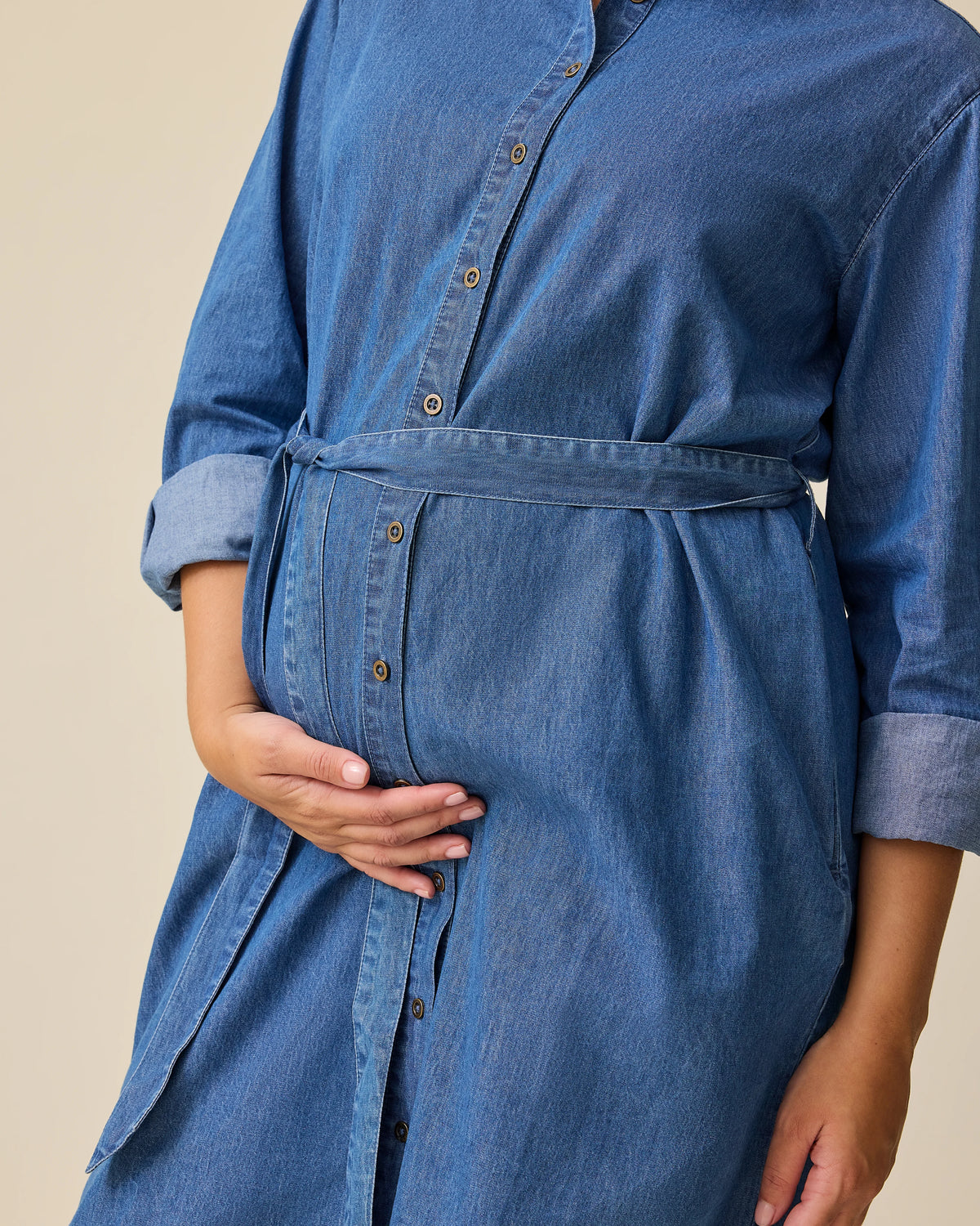 Close up of denim belt on Denim Maternity & Nursing Shirt Dress in Dark Wash on a beige background.