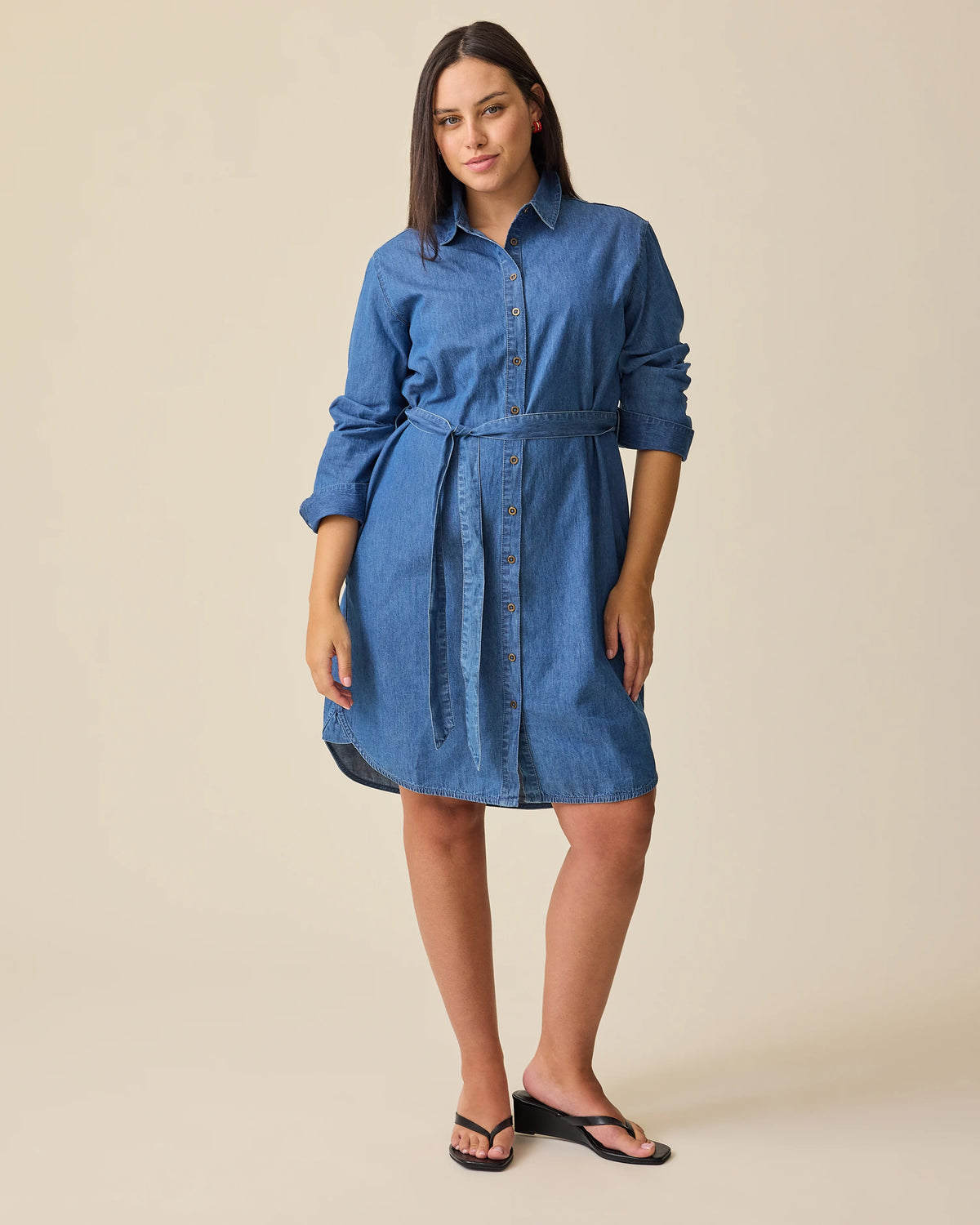 Model is wearing Denim Maternity & Nursing Shirt Dress in Dark Wash on a beige background.@model_info:Brianna is 5'8" and wearing a Medium.