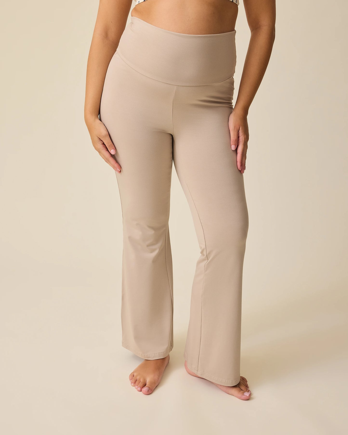Front view of model wearing Bamboo Flex Maternity & Postpartum Flare Pant in Sandstone on a beige background. @model_info:Brianna is 5'8" and wearing a Medium.