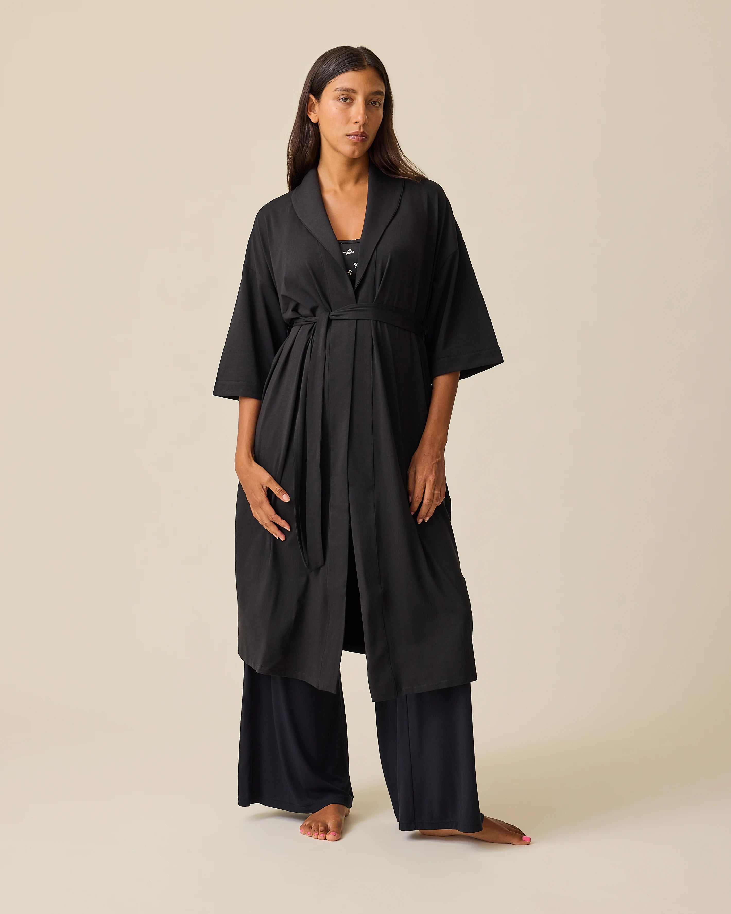 Model is wearing The Restore Cotton Blend Robe in Black and French Terry Racerback Nursing & Sleep Bra in Black Wildflower on a beige background. @model_info:Hayley is 5'7
