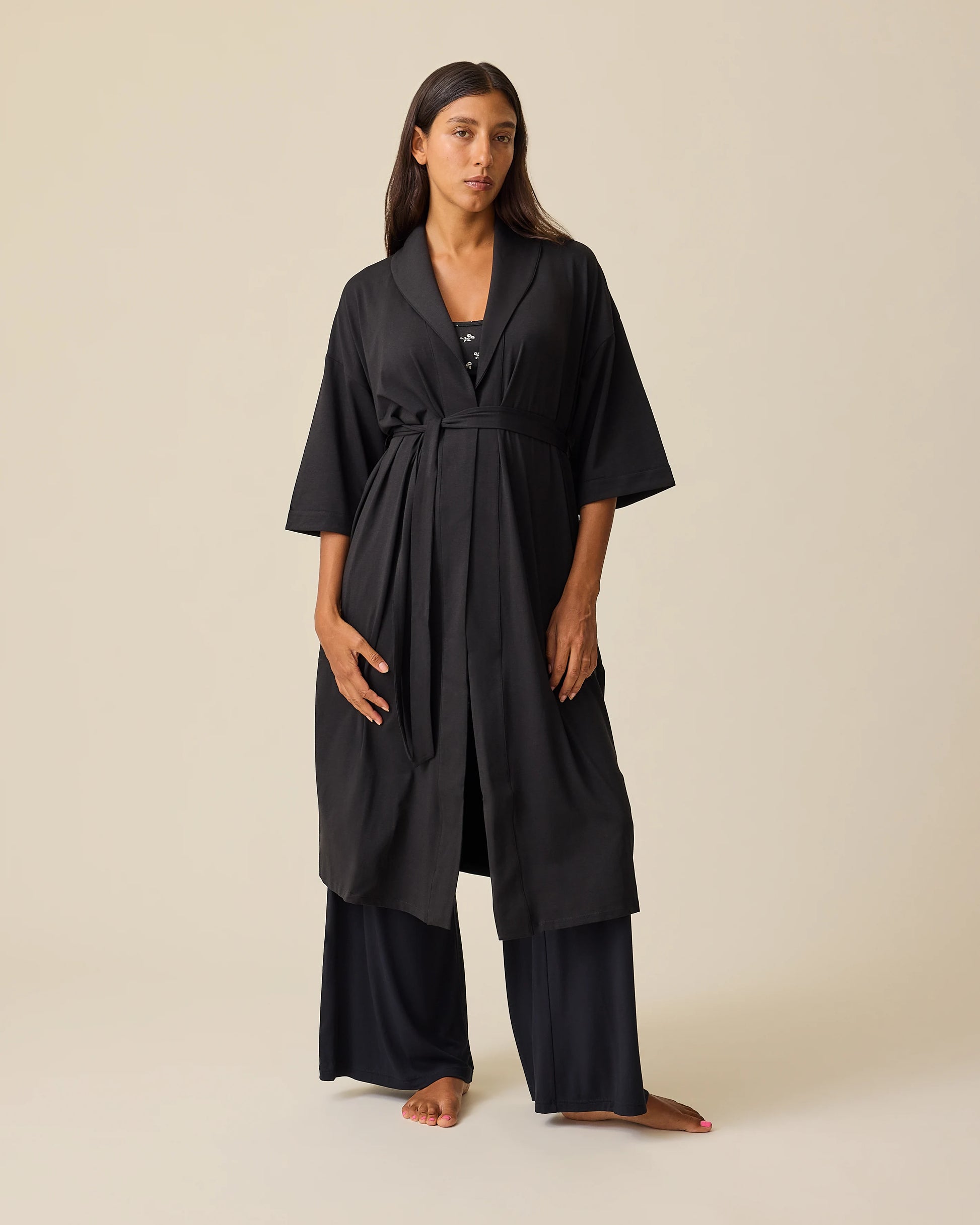 Model is wearing The Restore Cotton Blend Robe in Black and French Terry Racerback Nursing & Sleep Bra in Black Wildflower on a beige background. @model_info:Hayley is 5'7" and wearing a Small.