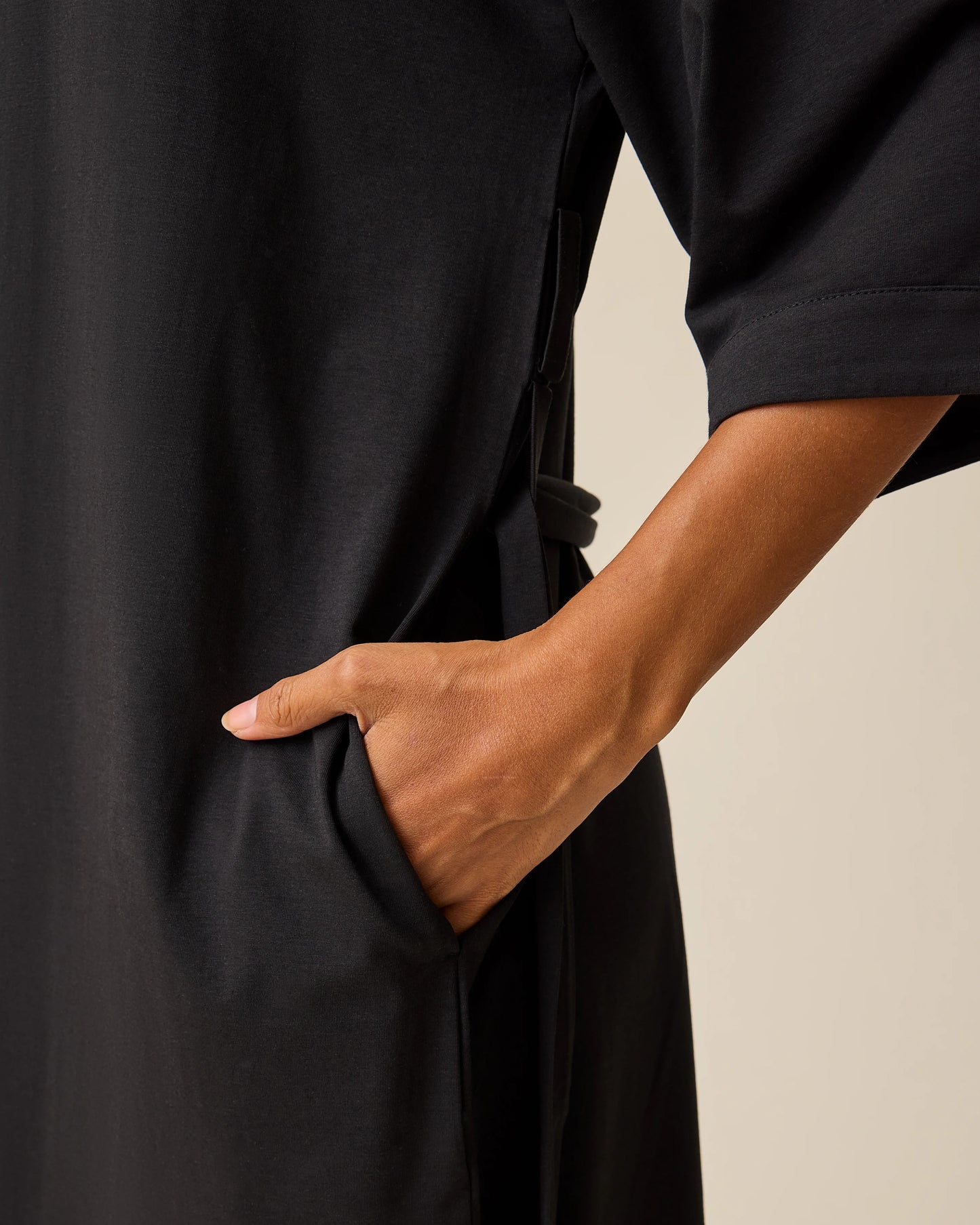 Close up of pocket on The Restore Cotton Blend Robe in Black on a beige background.