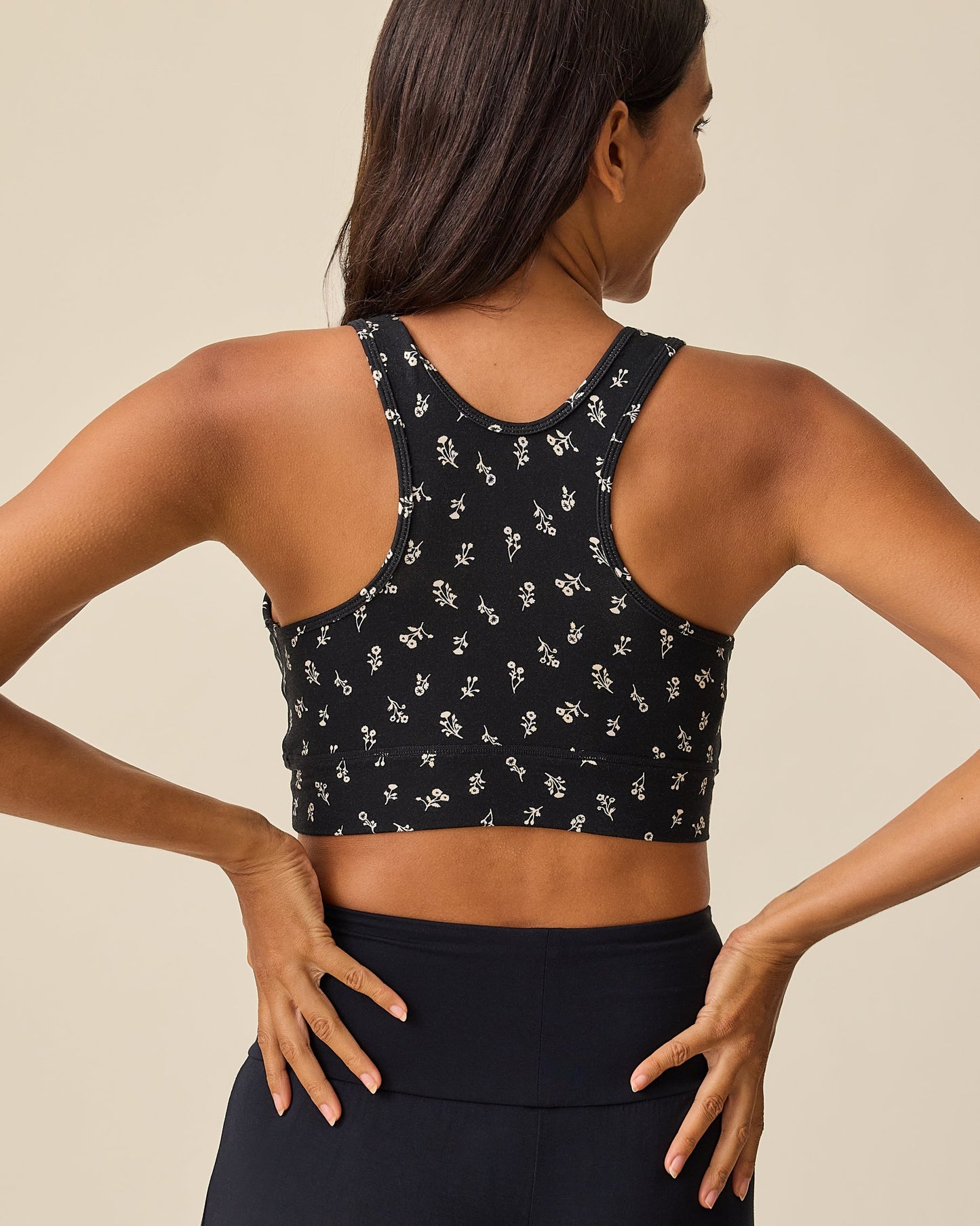 Back view of the French Terry Racerback Nursing & Sleep Bra in Black Wildflower pattern on a beige background.
