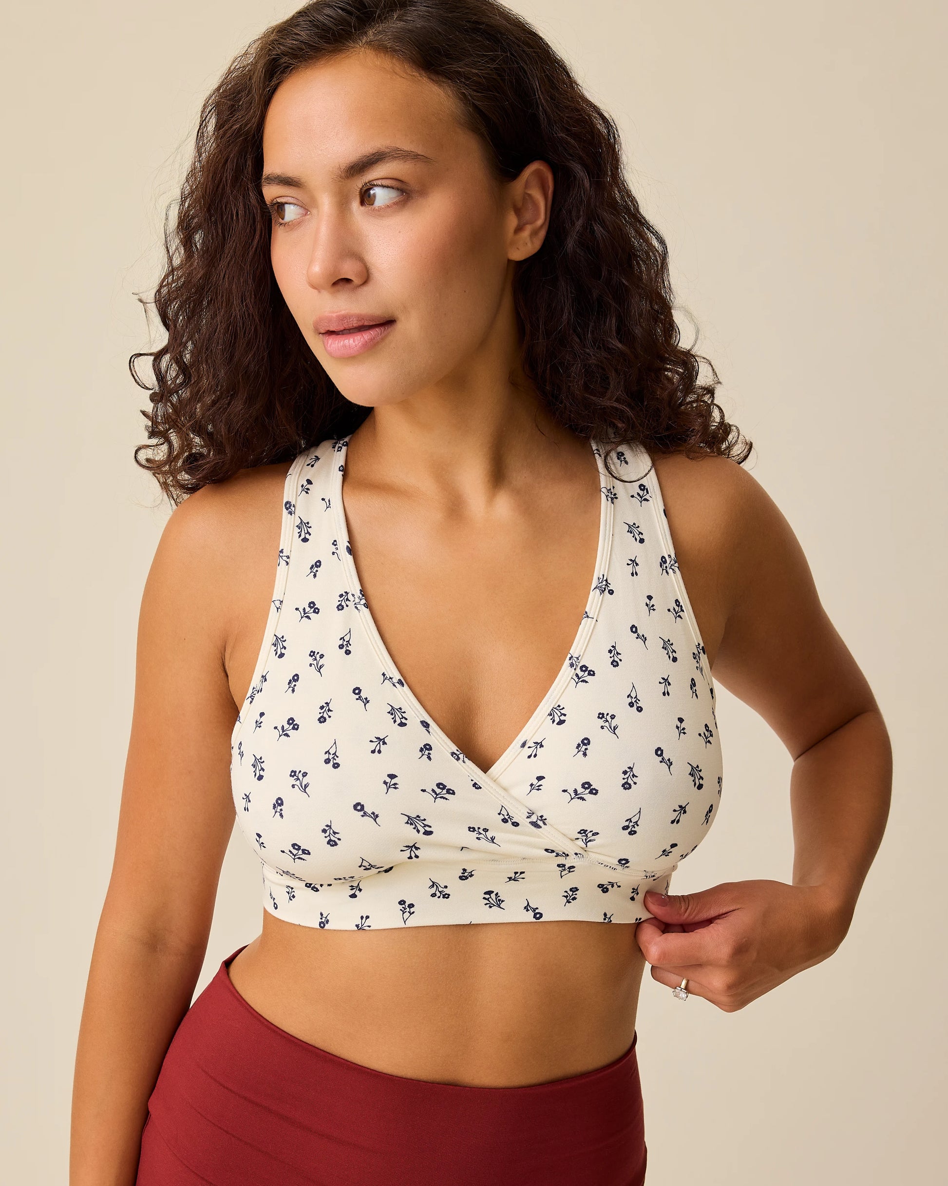 Model is wearing French Terry Racerback Nursing & Sleep Bra in Ivory Wildflower on a beige background.