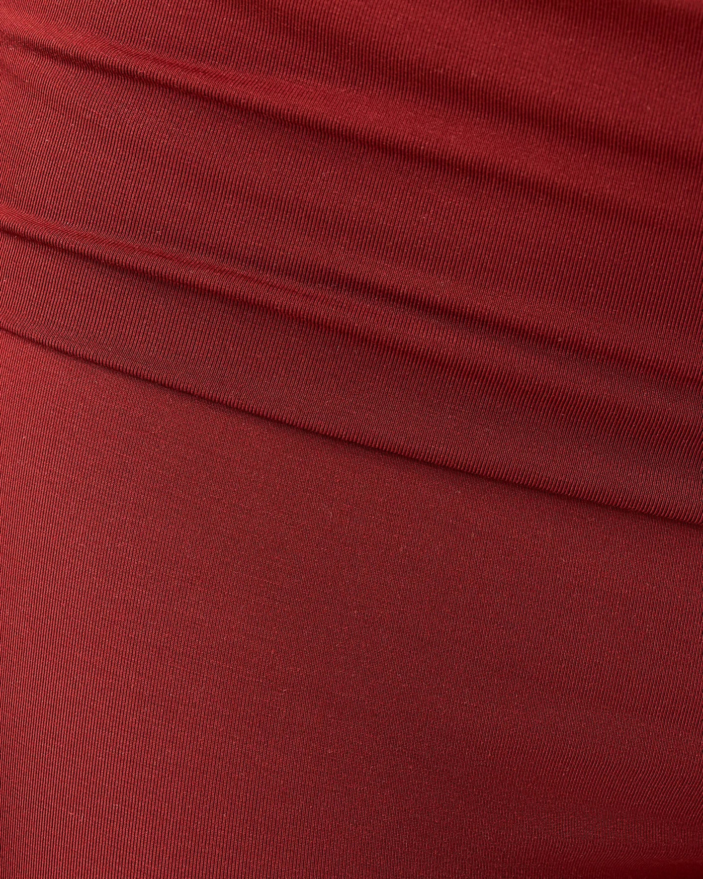 Close up of soft material on the Bamboo Flex Maternity & Postpartum Flare Pant in Auburn on a beige background. 