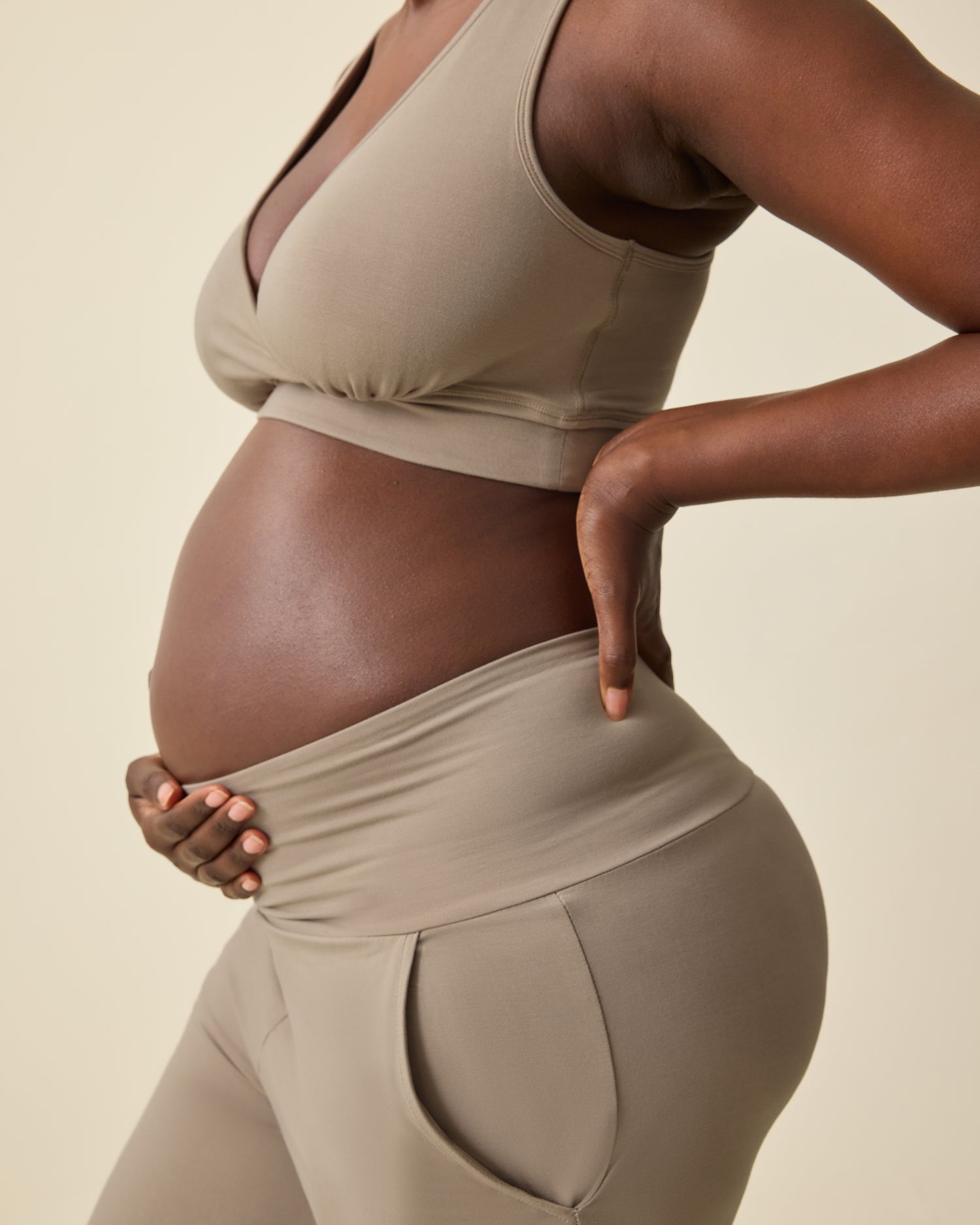 Side view of pregnant model wearing French Terry Racerback Nursing & Sleep Bra in Sandstone and Bamboo Wide Leg Maternity & Postpartum Lounge Pant in Sandstone on a beige background.