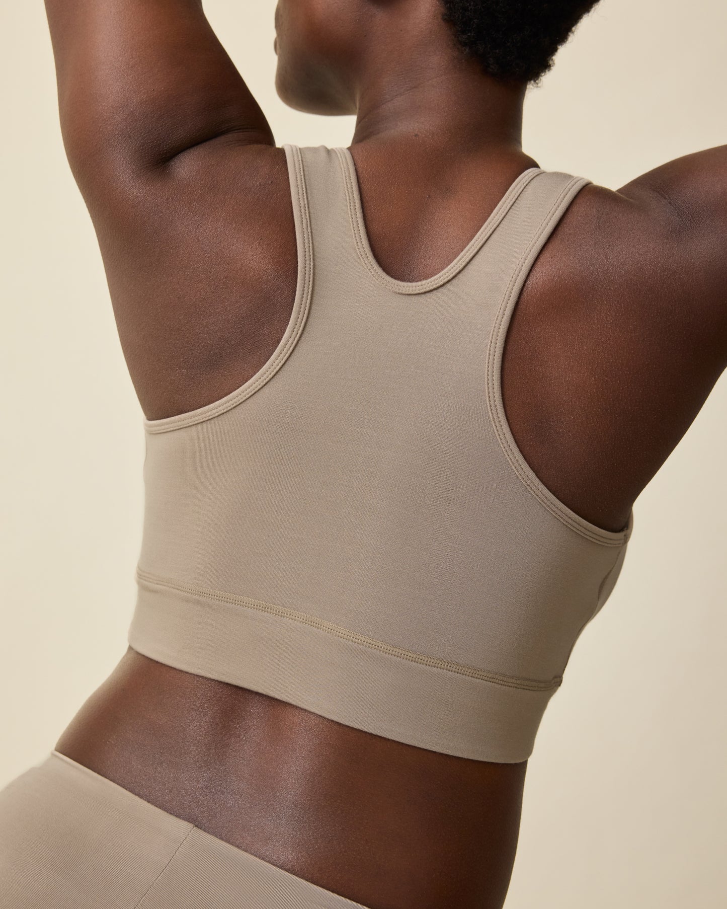 Back view of Model wearing French Terry Racerback Nursing & Sleep Bra in Sandstone on a beige background