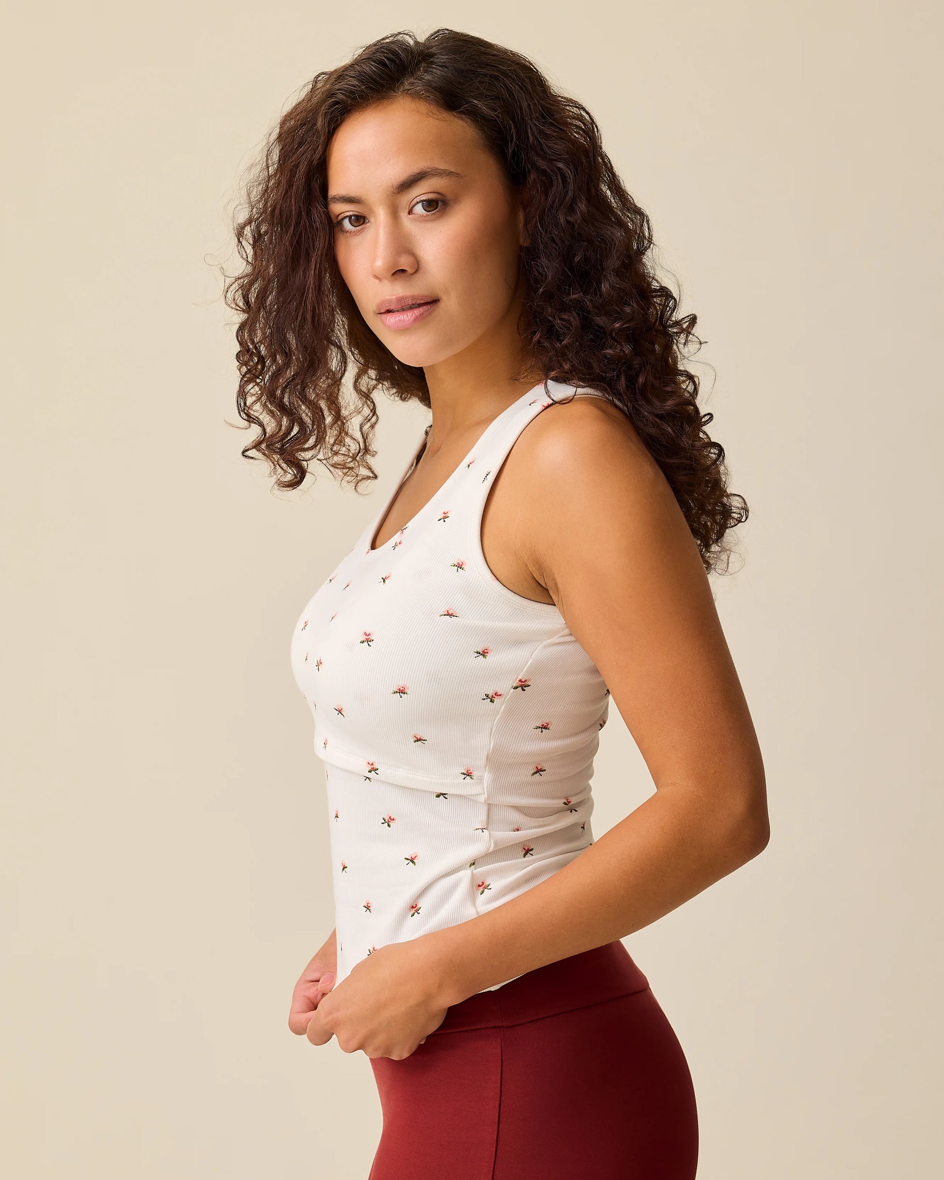 Side view of model wearing French Terry Racerback Tank in Ivory Wildflower on a beige background.