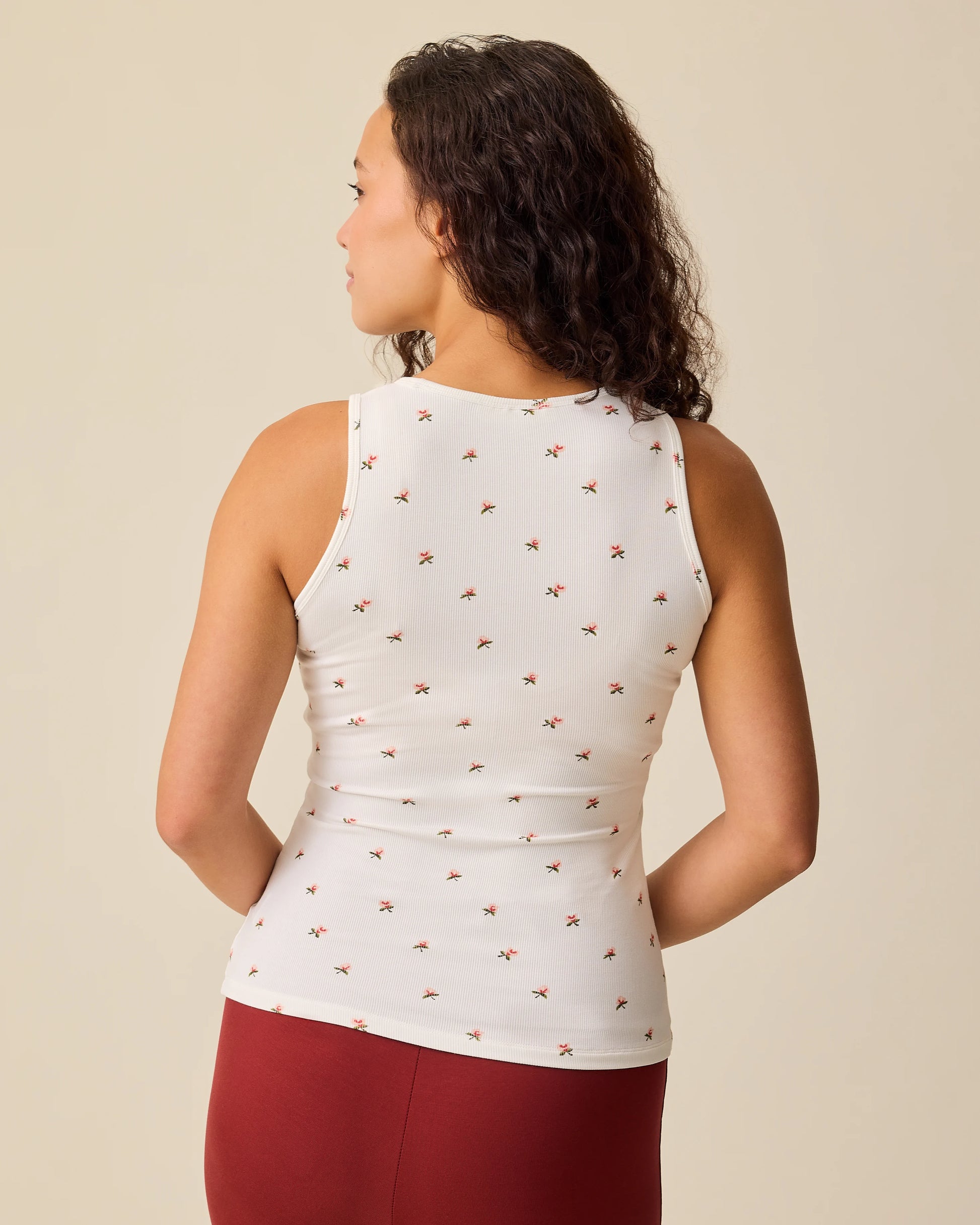 Back view of model wearing French Terry Racerback Tank in Ivory Wildflower on a beige background.