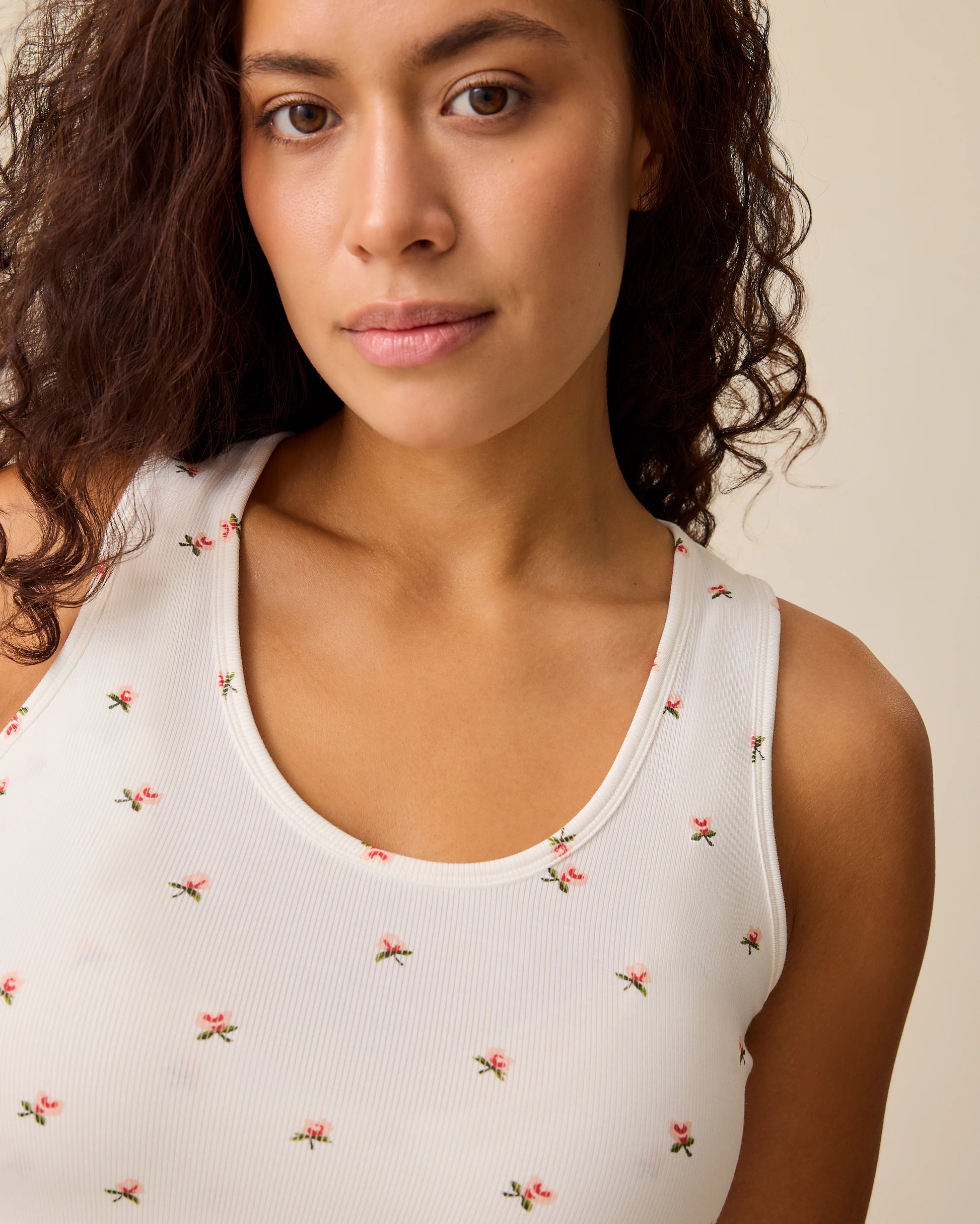 Close up of model wearing French Terry Racerback Tank in Ivory Wildflower on a beige background.
