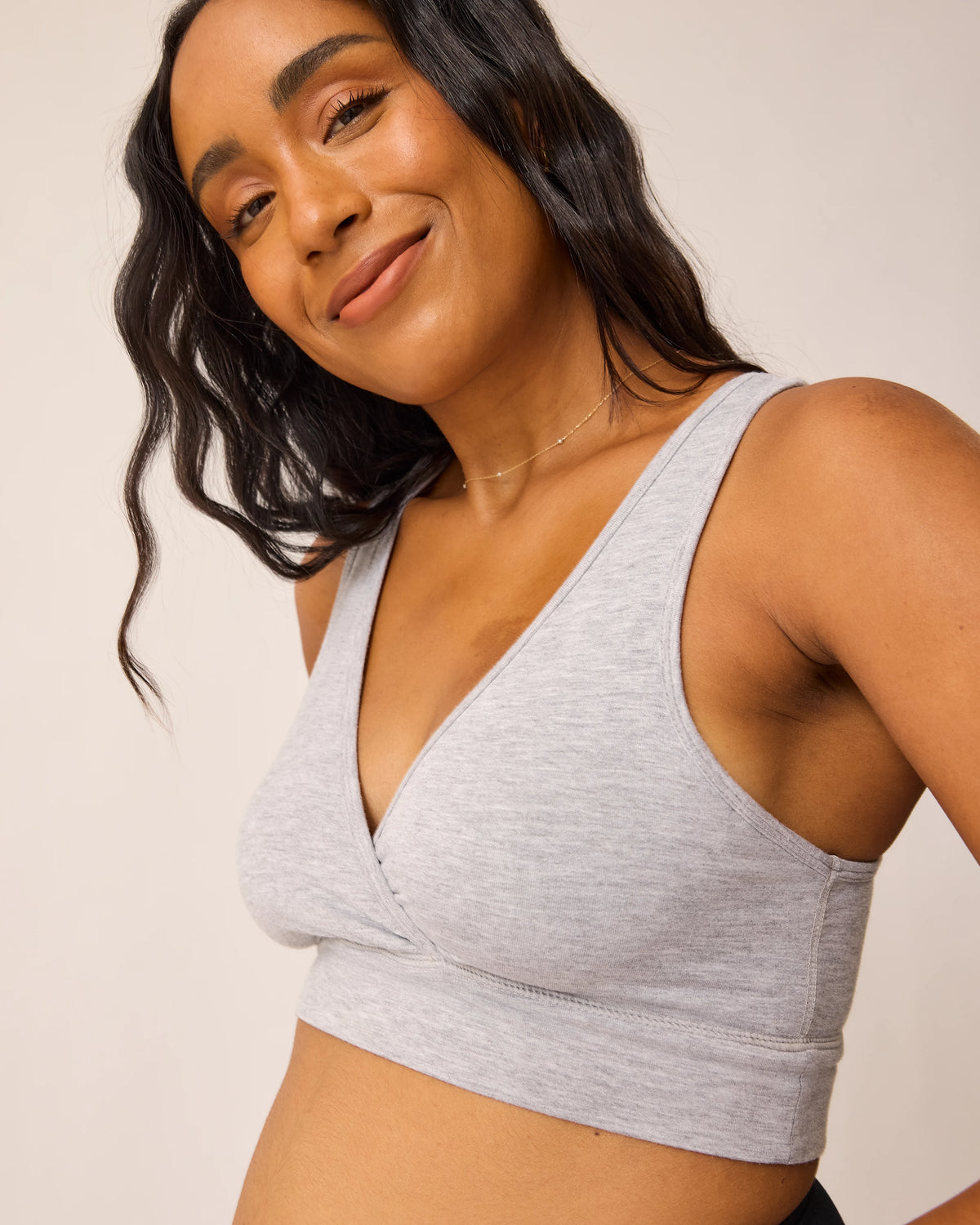 Woman wearing the French Terry Racerback Nursing & Sleep Bra in grey heather against a beige background