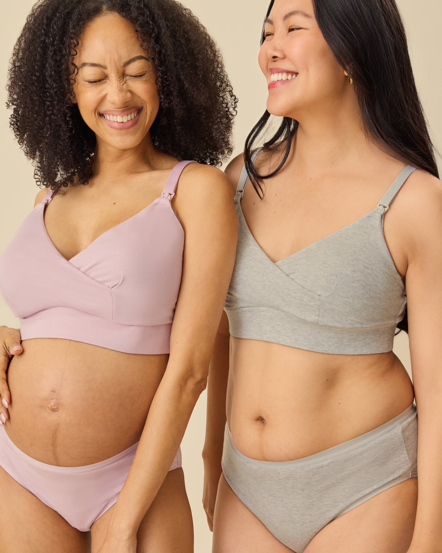 Pregnant model on the left is wearing SoftStretch Cotton Nursing Bra and SoftStretch Cotton Maternity & Postpartum Brief in Lilac Mist. Postpartum model on the right is wearing SoftStretch Cotton Nursing Bra and SoftStretch Cotton Maternity & Postpartum Hipster in Grey Heather on a beige background. 