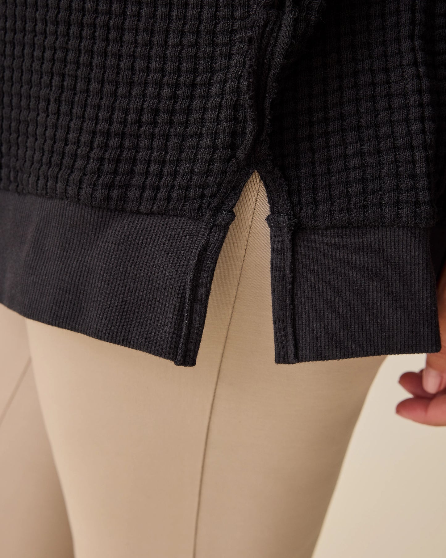 Side detail close up of hidden zipper on the Joelle Thermal Maternity & Nursing Top in Black on a beige background.