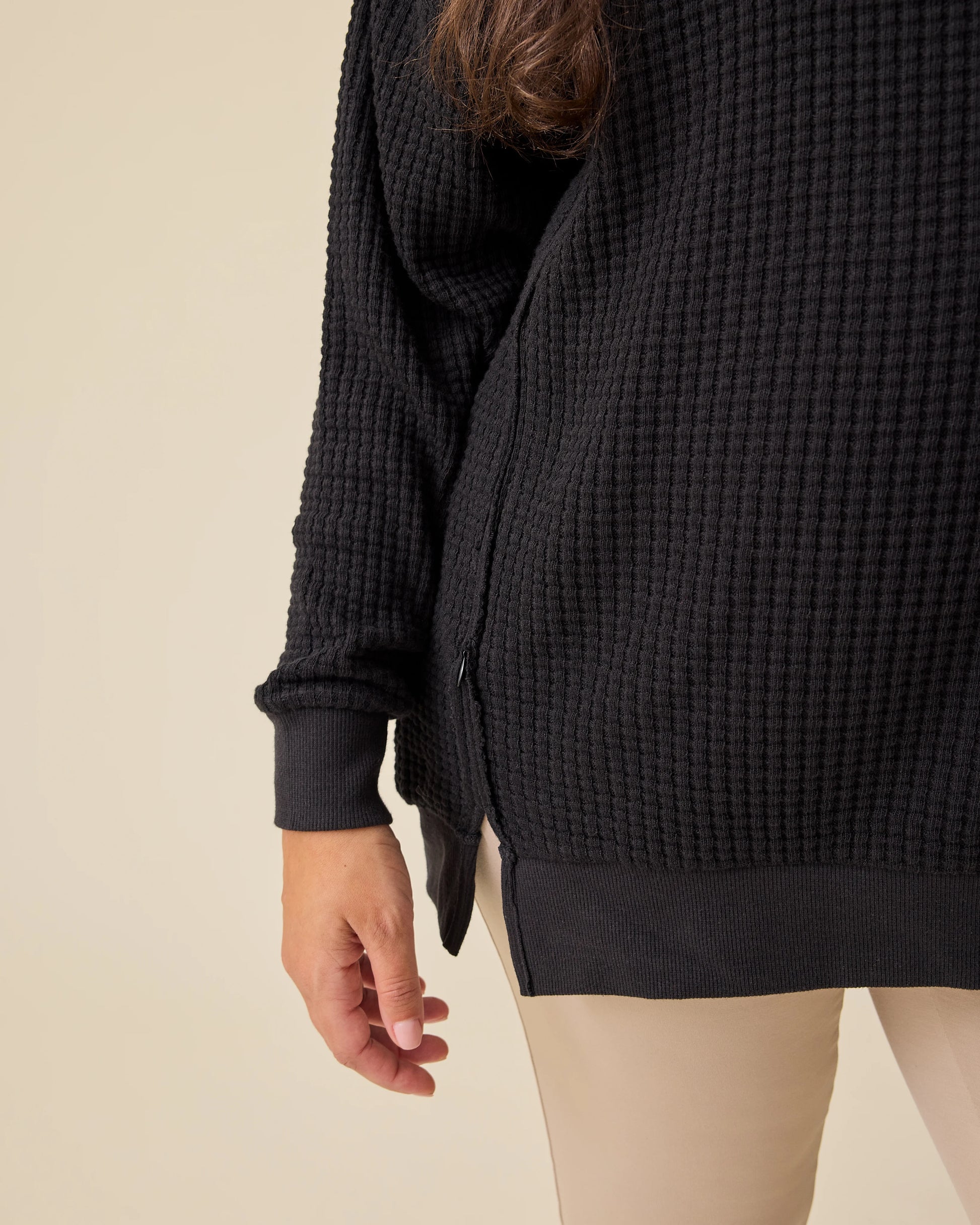 Close up detail of the hidden zipper for nursing access on the Joelle Thermal Maternity & Nursing Top in Black on a beige background.