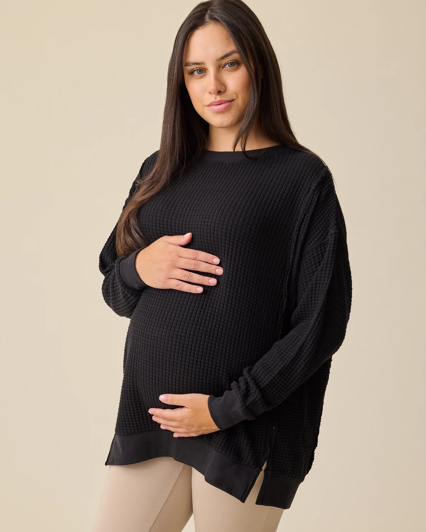 Model is wearing the Joelle Thermal Maternity & Nursing Top in Black on a beige background. @model_info:Brianna is wearing a Small.