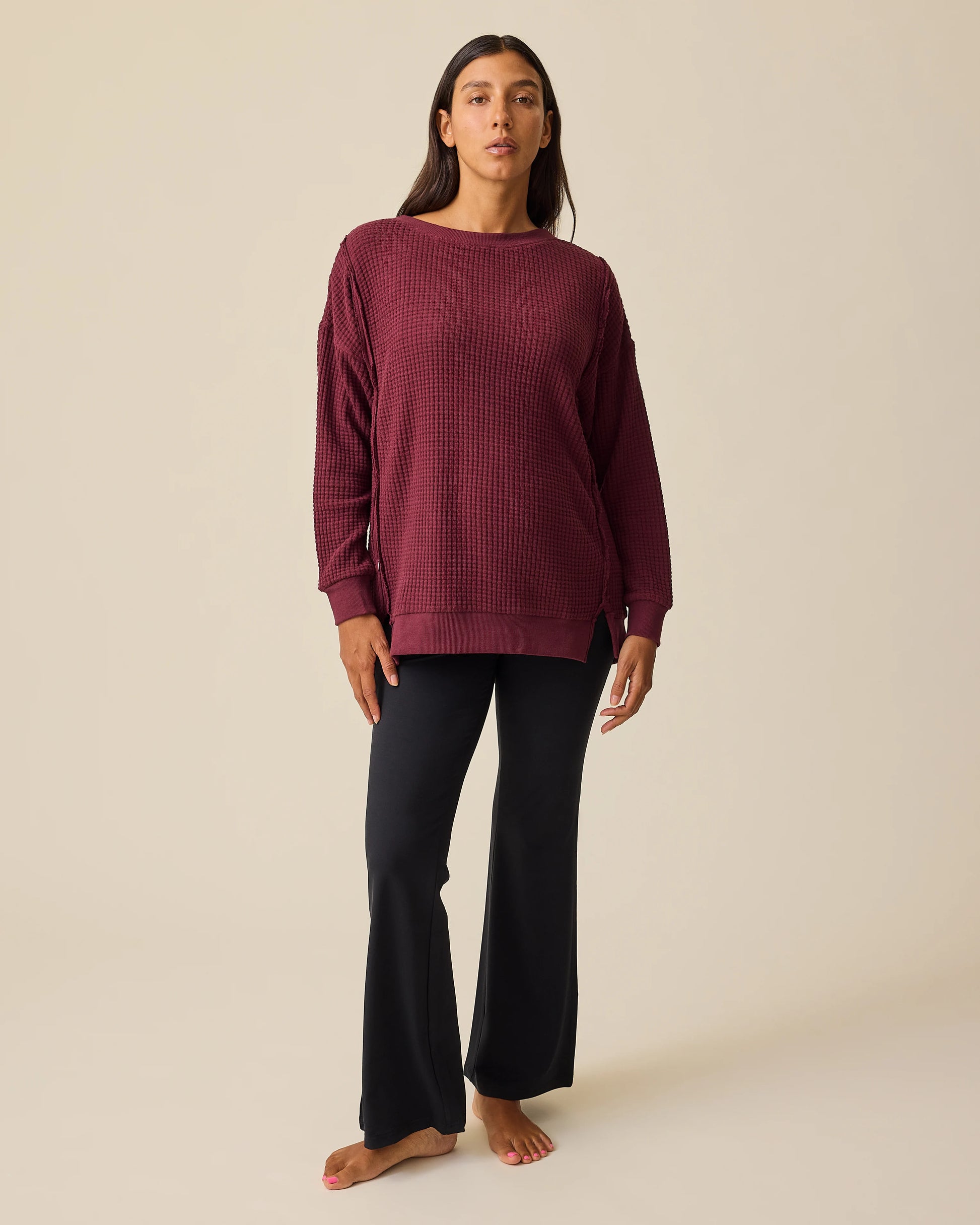 Model is wearing Joelle Thermal Maternity & Nursing Top in Garnet with black pants on a beige background.