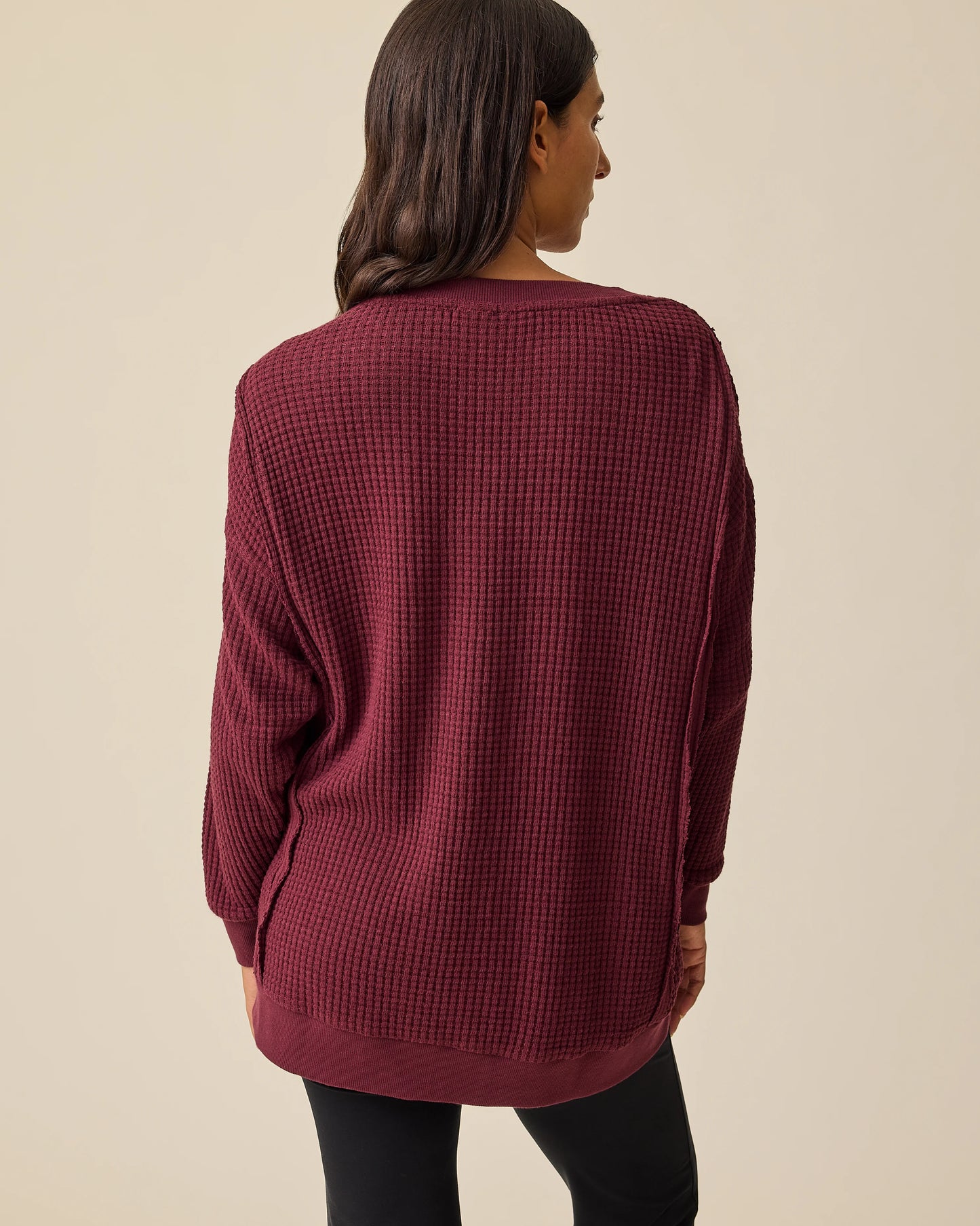 Back view of model wearing Joelle Thermal Maternity & Nursing Top in Garnet with black pants on a beige background.