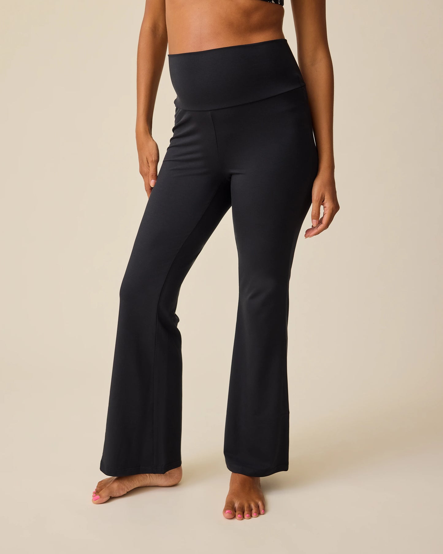 Front view of model wearing Bamboo Flex Maternity & Postpartum Flare Pant in Black on a beige background. @model_info:Hayley is 5'7" and wearing a Small.