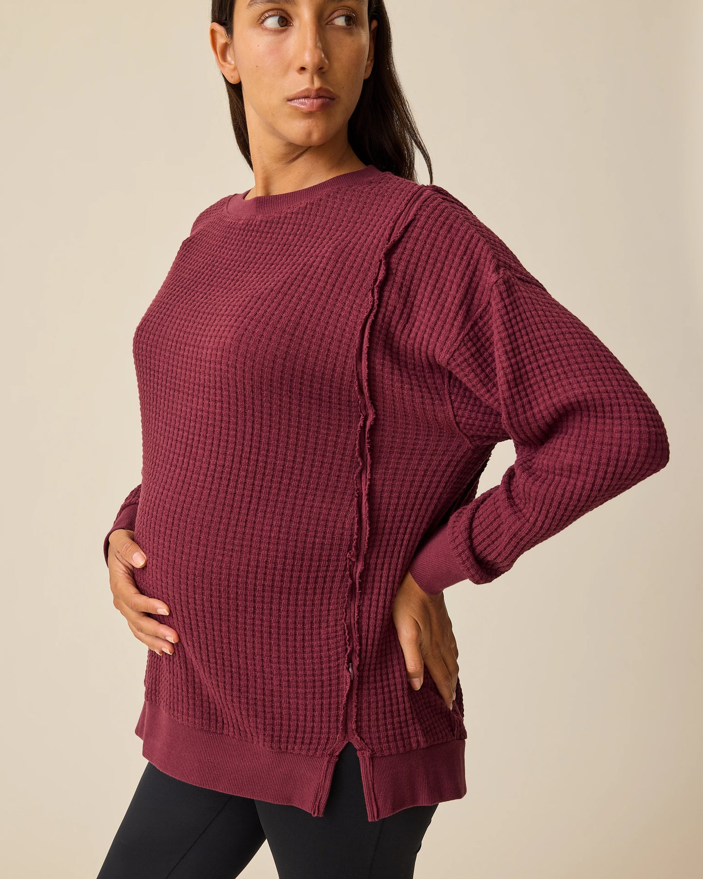 Model is wearing the Joelle Thermal Maternity & Nursing Top in Garnet with black pants on a beige background.