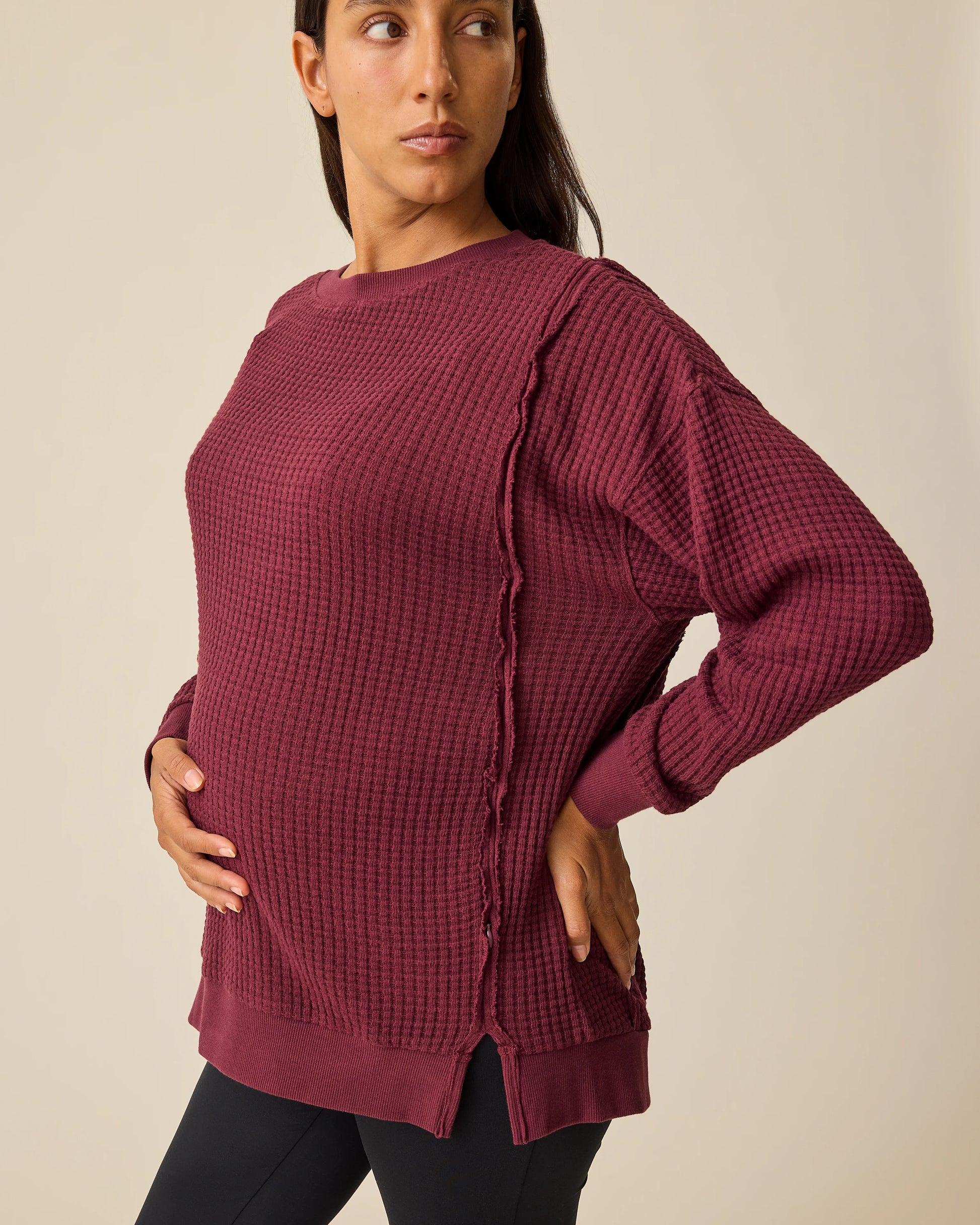Model is wearing the Joelle Thermal Maternity & Nursing Top in Garnet with black pants on a beige background.