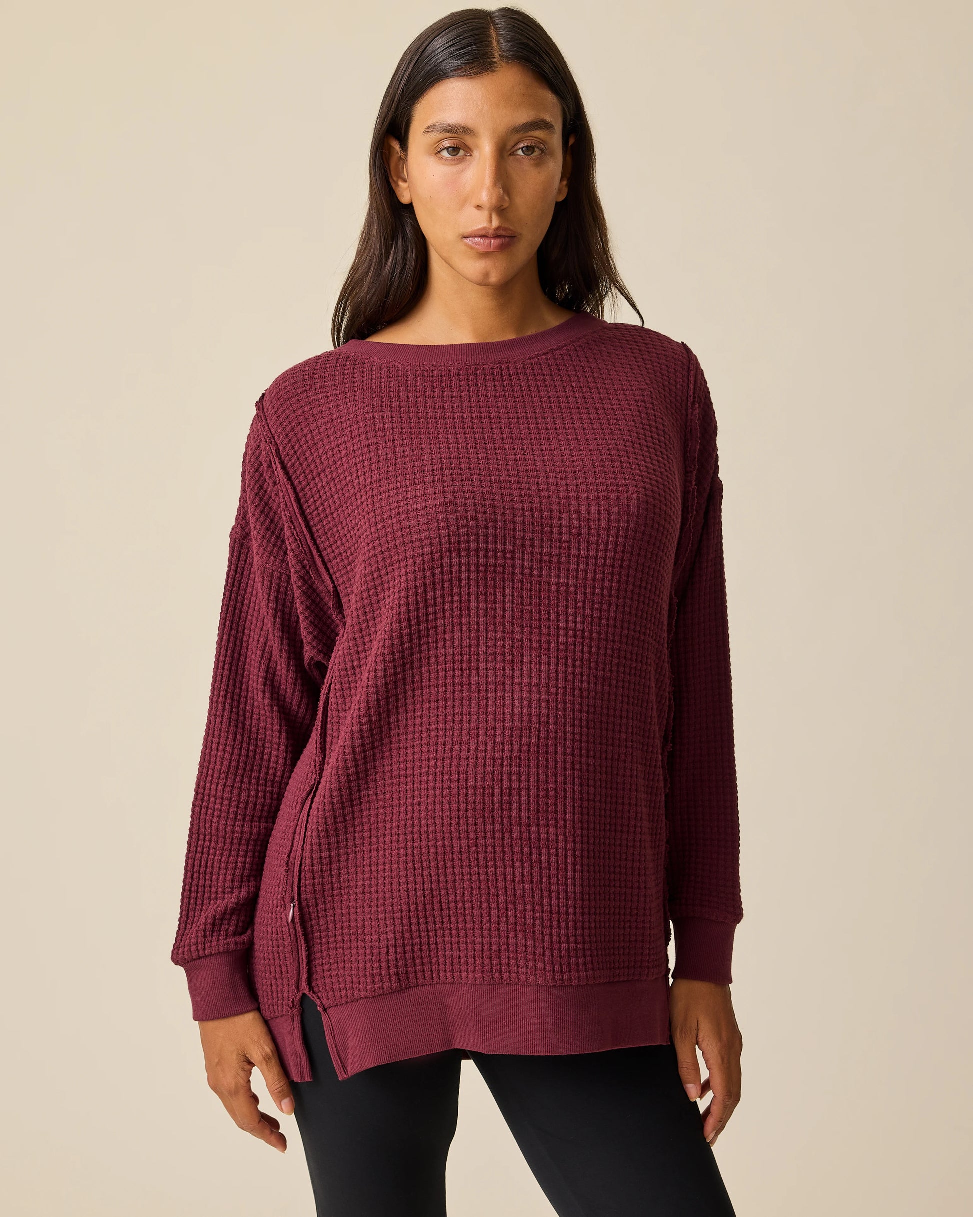 Model is wearing the Joelle Thermal Maternity & Nursing Top in Garnet with black pants on a beige background. @model_info:Hayley is wearing a Small.