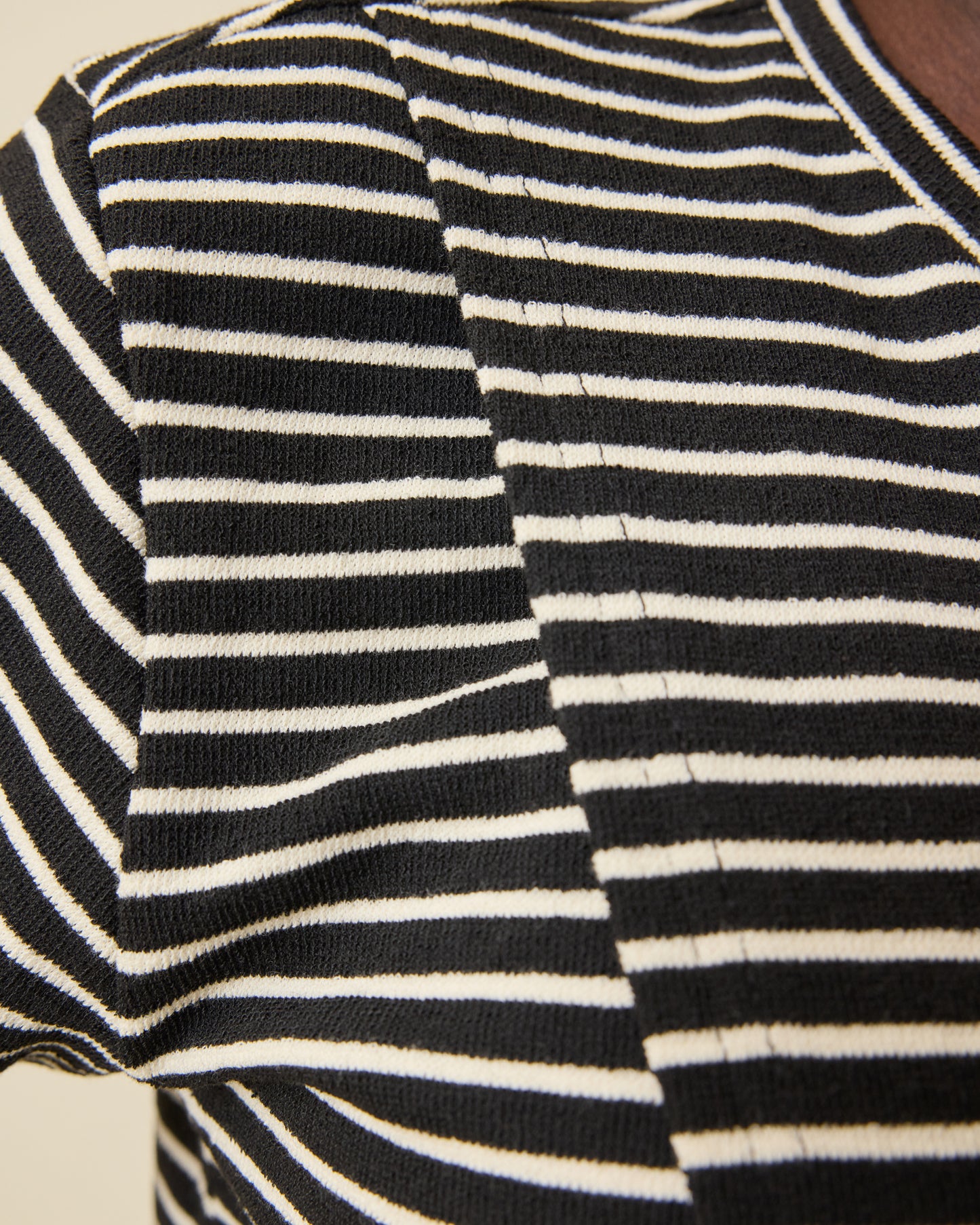 Close up of lift-up panel for breastfeeding access on the Luxe Terry Maternity & Nursing Split Hem T-shirt in Black & Ivory Stripe on a beige background.