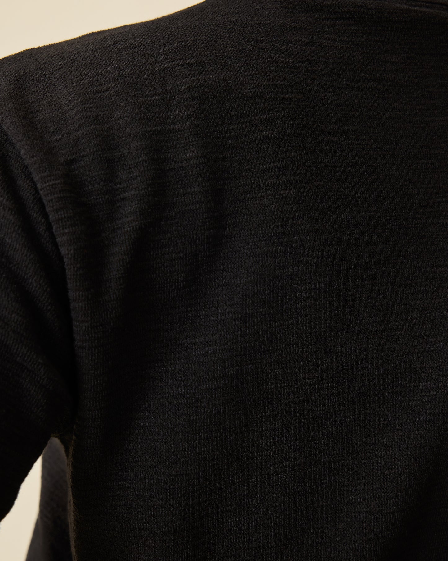 Close up of soft material on Luxe Terry Maternity & Nursing Split Hem T-shirt in Black on a beige background.