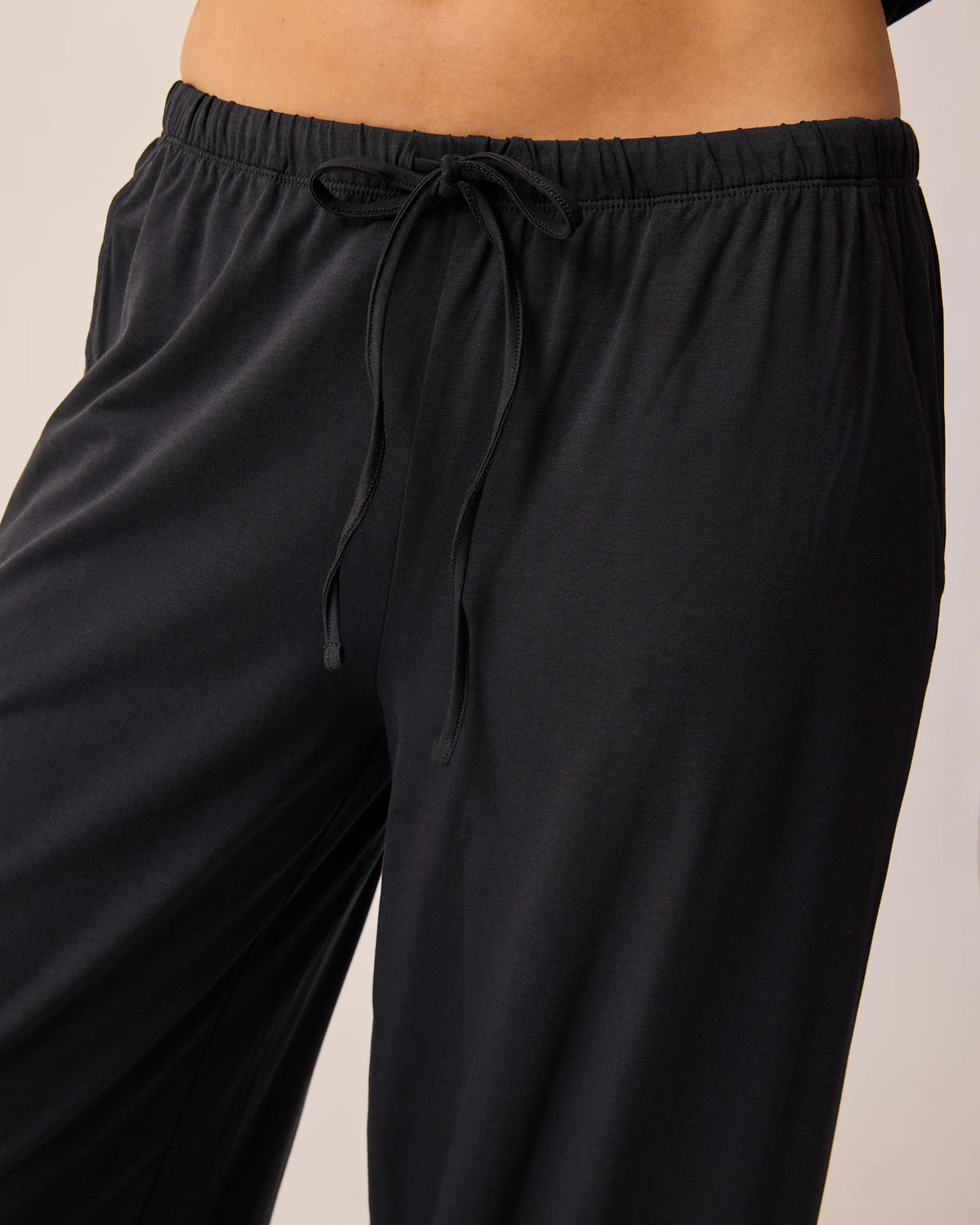 Close up of the pants of the Maternity & Nursing Three-Piece Pajama Set in Black, on a beige background.