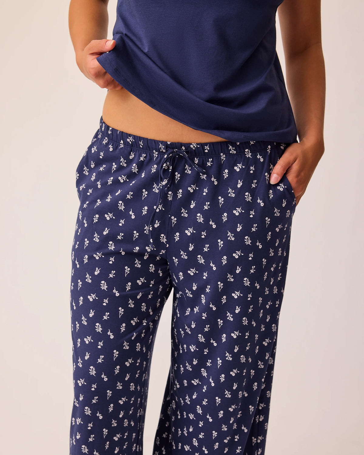 Model is wearing just tank and pants of the Maternity & Nursing Three-Piece Pajama Set in Navy on a beige background.