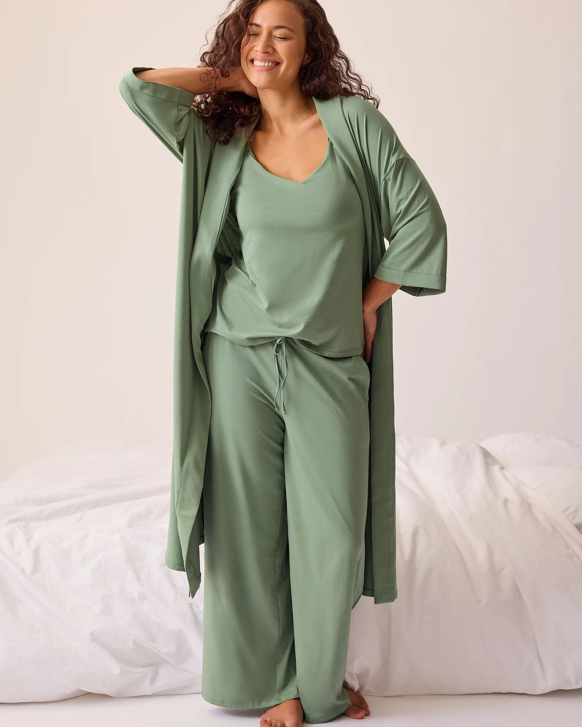 Model is wearing Maternity & Nursing Three-Piece Pajama Set in Sage on a beige background with pillows on floor.