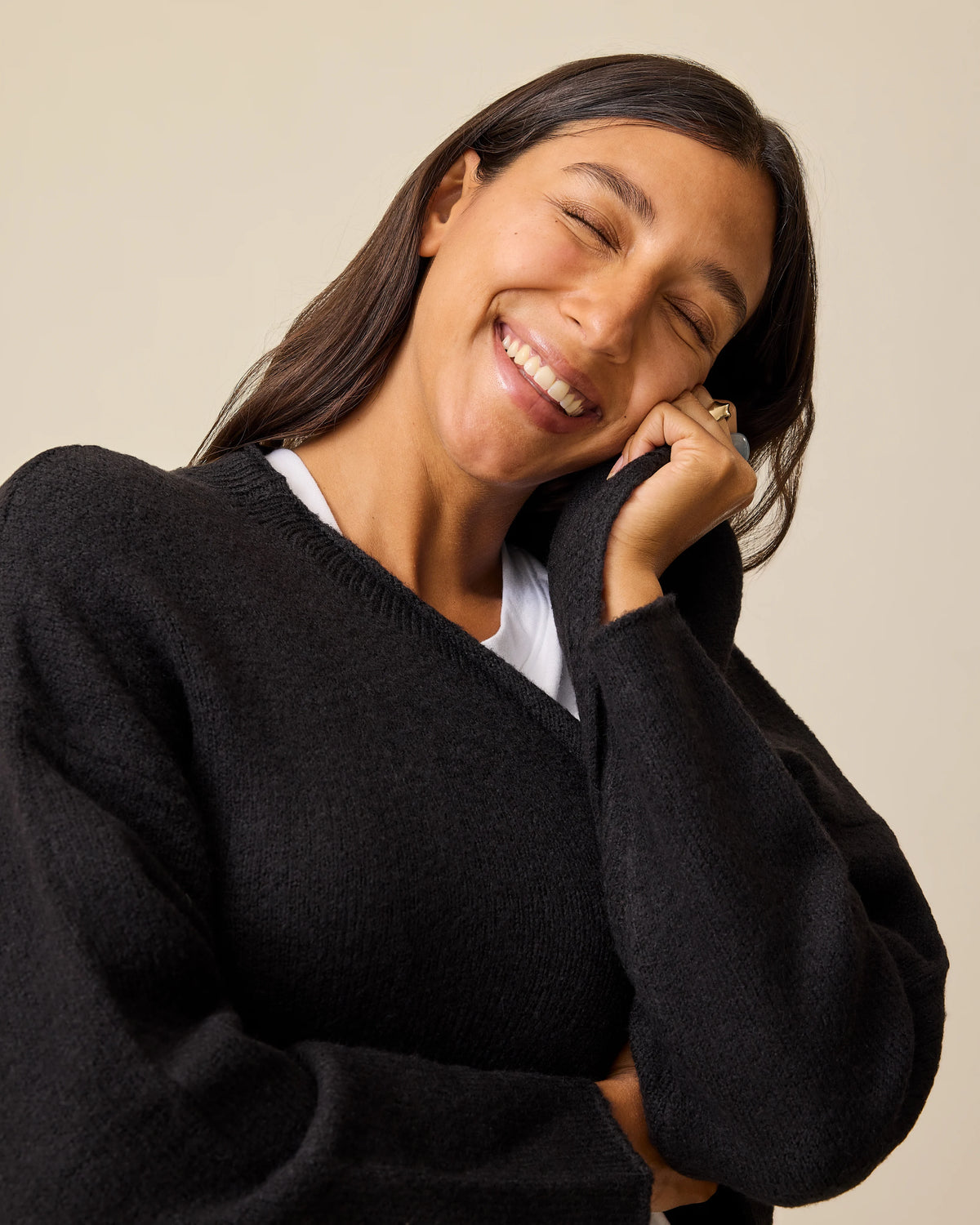 Model is enjoying softness of the Ultra Soft Maternity & Postpartum Cardigan in Black, Wide Leg Maternity & Postpartum Jean in Medium Wash and a white nursing top, on a beige background.