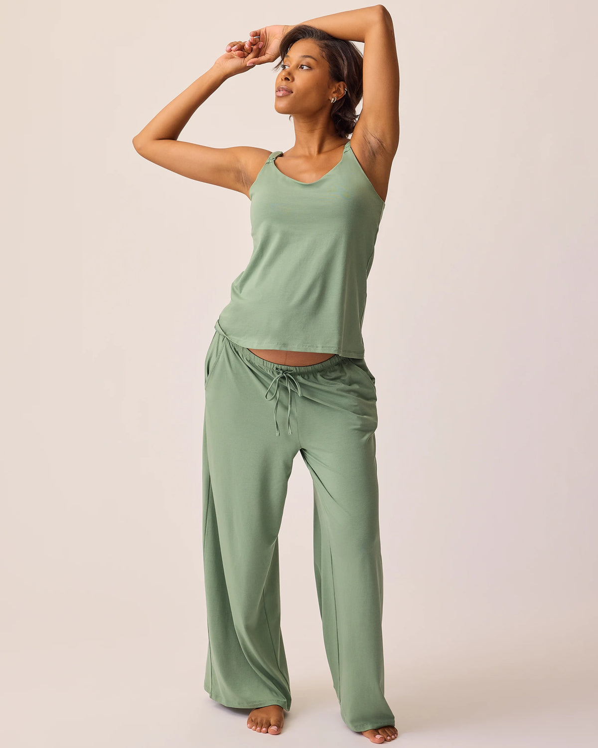 Model is wearing pants and tank of the Maternity & Nursing Three-Piece Pajama Set in Sage on a beige background.