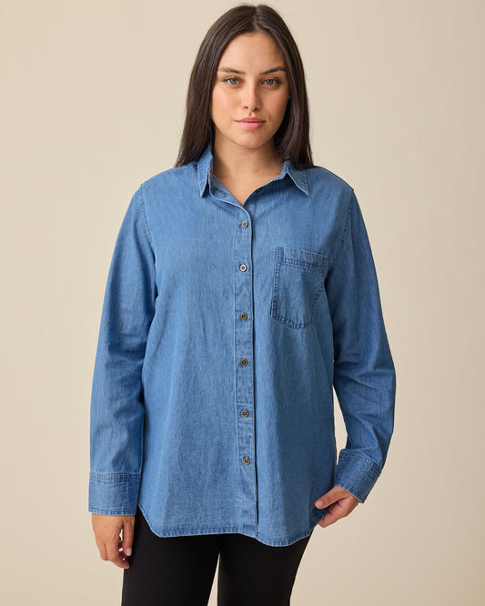 Model is wearing Denim Maternity & Nursing Button Up Shirt in Medium Wash and Maternity Ponte Straight Leg Pant in Black on a beige background.@model_info:Brianna is wearing a Medium.