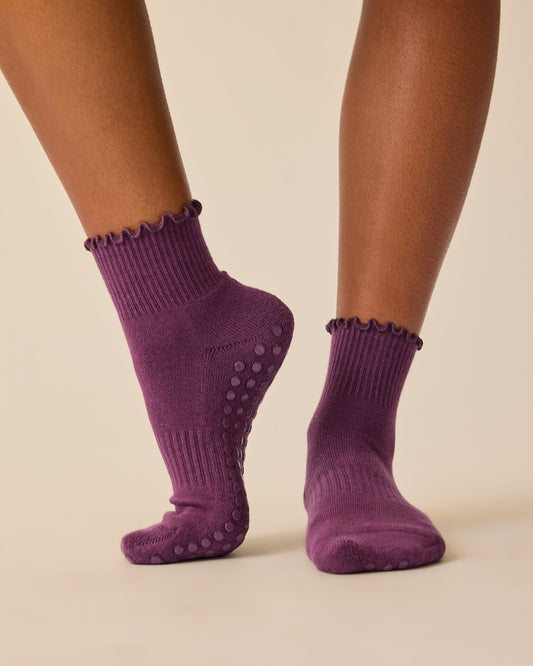 Model is wearing Non-Slip Ruffle Ankle Socks in Burgundy Plum on a beige background.
