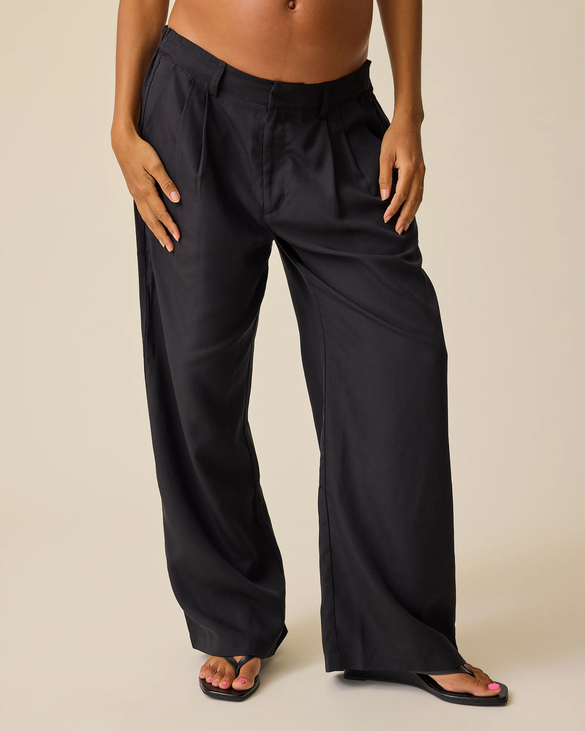Model is wearing Maternity & Postpartum Wide Leg Trouser in Black on a beige background.@model_info:Hayley is 5'7" and wearing a Small.