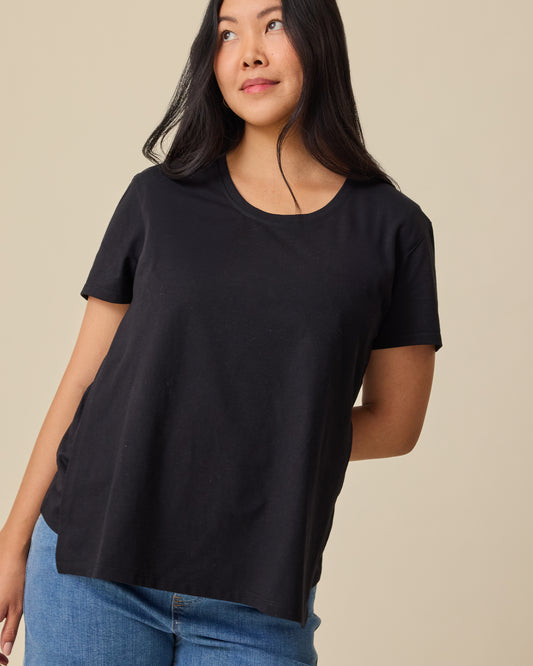Model showing nursing access on Relaxed Cotton Maternity & Nursing T-shirt in Black on a beige background. @model_info:Theresa is wearing a Small.