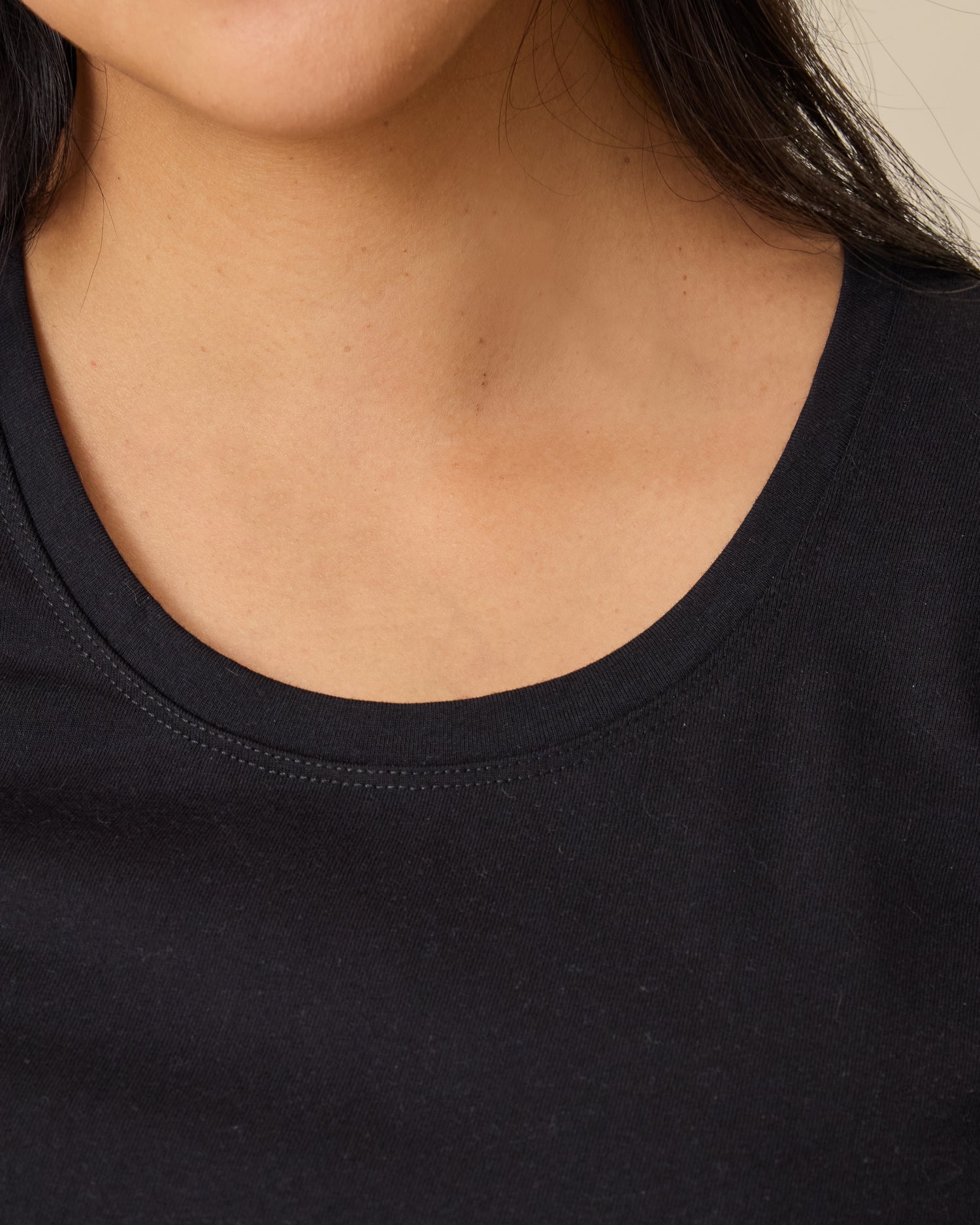 Close up of neckline of Relaxed Cotton Maternity & Nursing T-shirt in Black on a beige background.