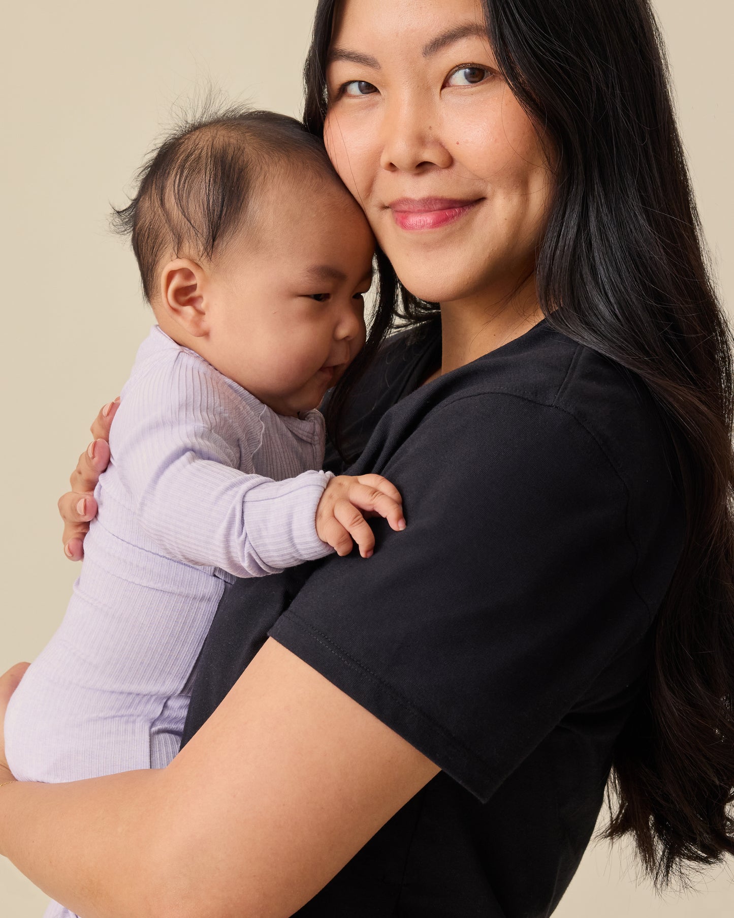 Model holding baby and wearing Relaxed Cotton Maternity & Nursing T-shirt in Black on a beige background.