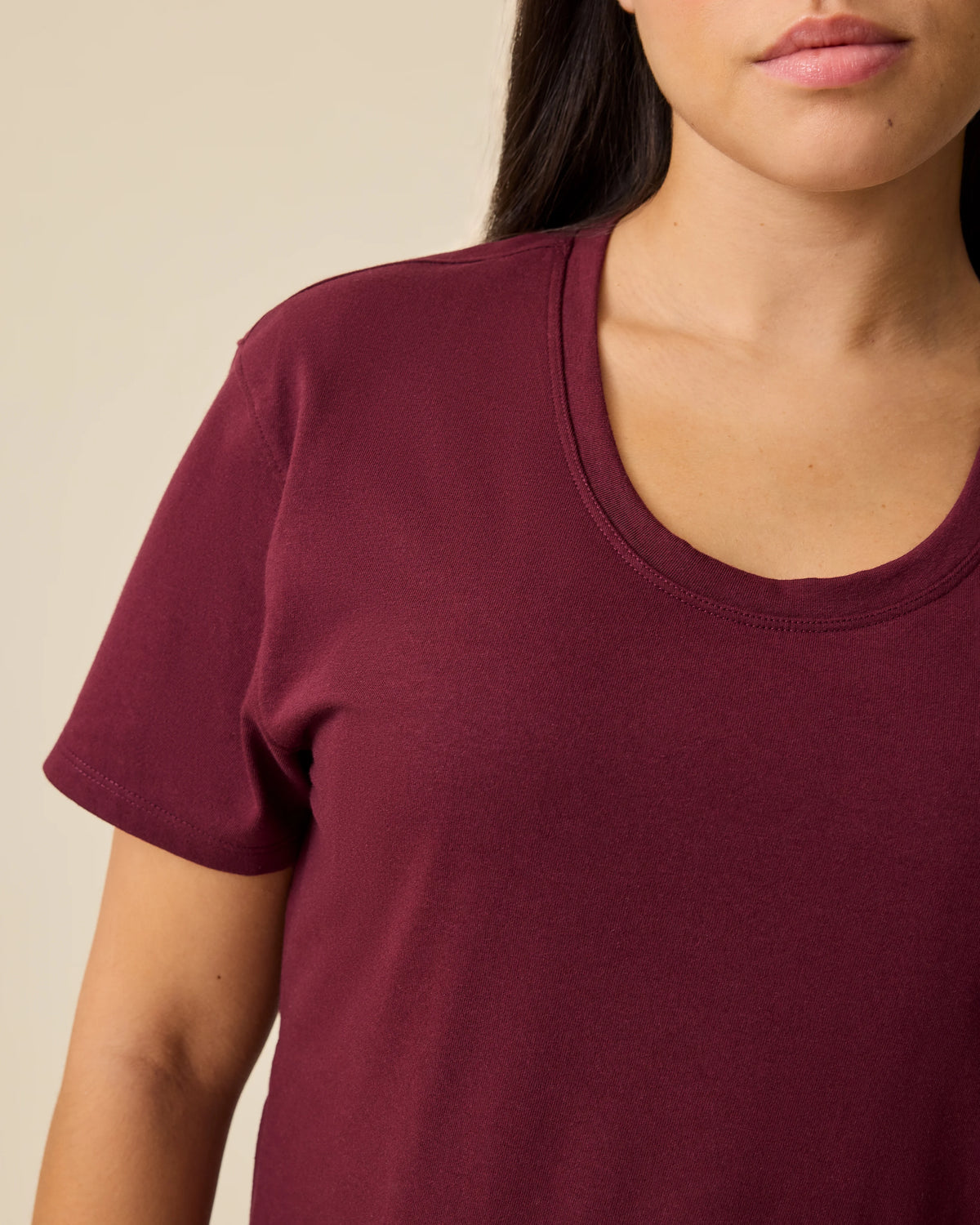 Close up of model wearing Relaxed Cotton Maternity & Nursing T-shirt in Fig on a beige background. 