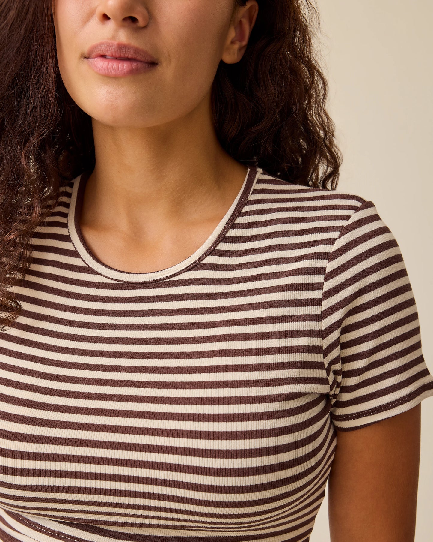 Close up of collar on the Ribbed Bamboo Crew Neck Nursing T-shirt in Chocolate & Ivory Stripe on a beige background.